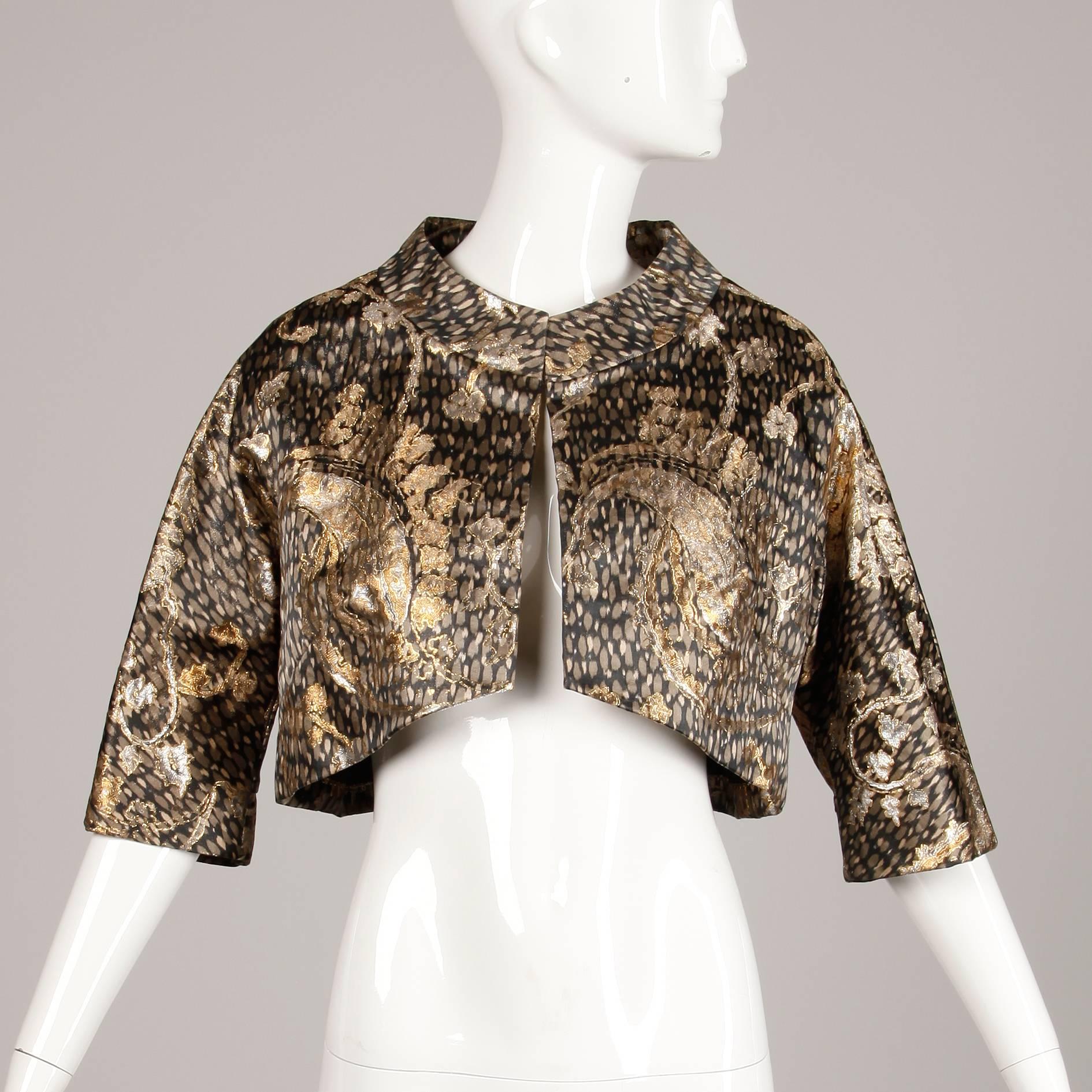 The silk fabric on this bolero is completely stunning in person! It is done in a metallic silk brocade. Gorgeous cropped cut with 3/4 length sleeves. Fully lined with front hook closure. Fits like a size small. The bust measures 42