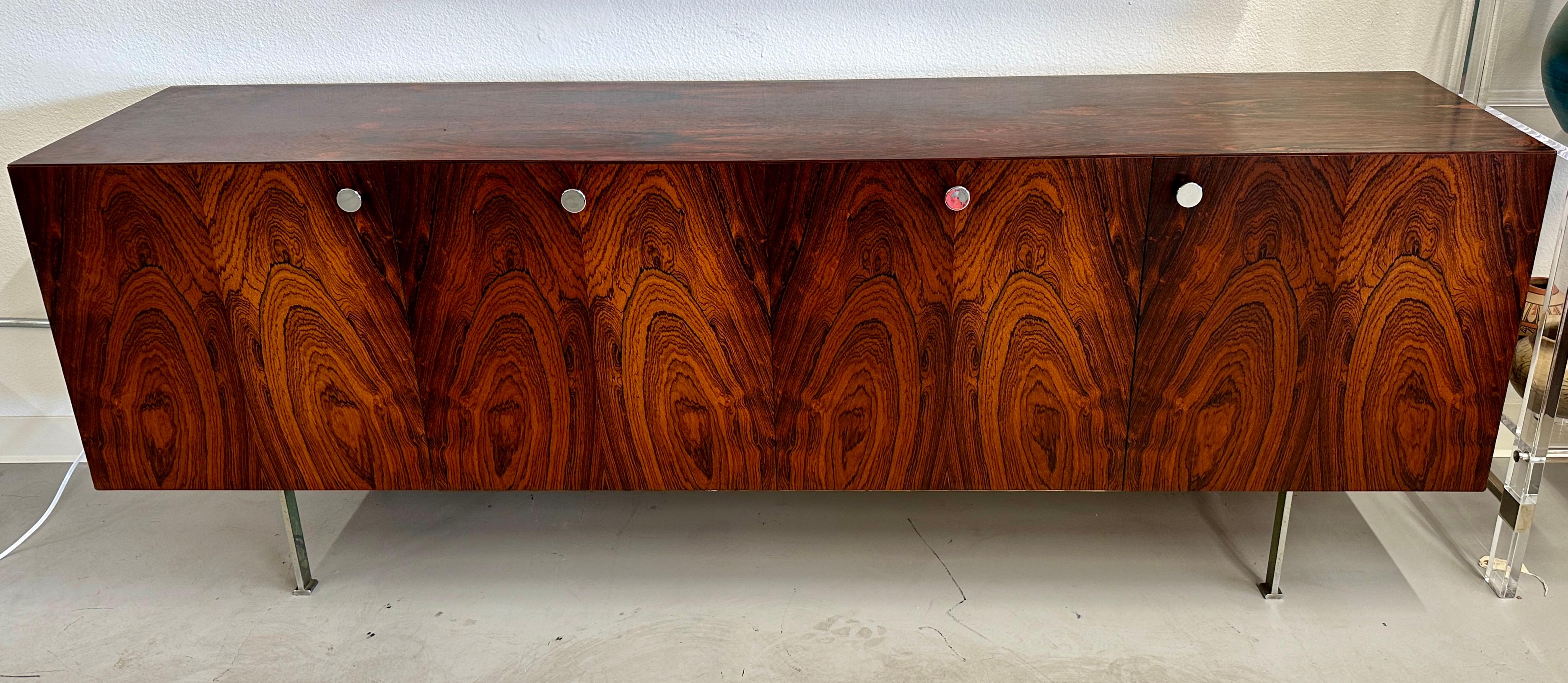 A stunning rosewood credenza designed by Poul Norreklit  for Georg Petersens of Denmark.  In original finish. Four drawers with two drop down fronts and two swing open fronts. One half shelf in original milk glass. Most of the original shelves are