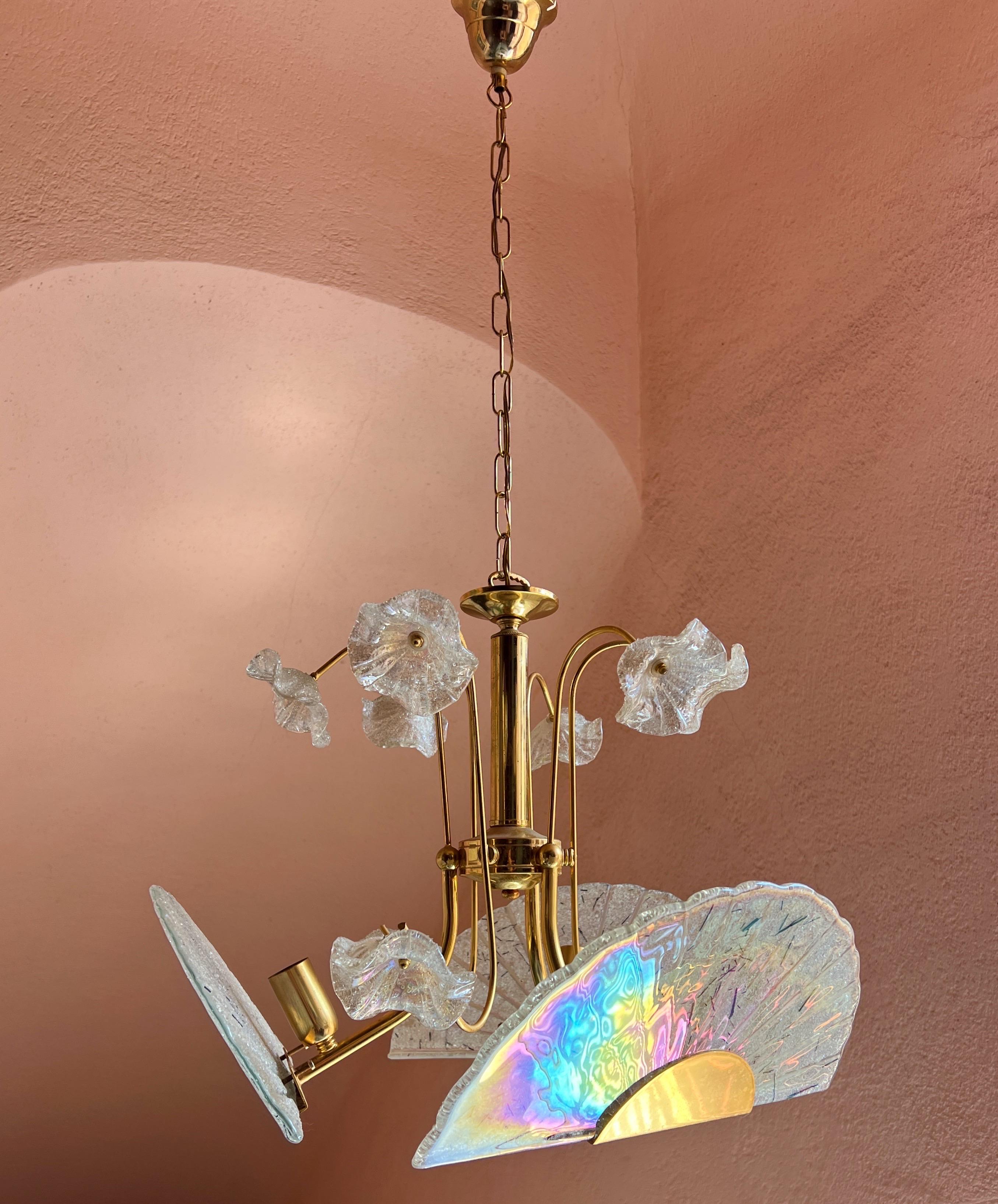 Lampadario in vetro di Murano degli anni '80 con tre dischi di vetro e delicati fiori in vetro di Murano. I dischi di vetro hanno un'incredibile finitura a olio che riflette i colori dell'arcobaleno.
Altezza con catena: 92 cm.