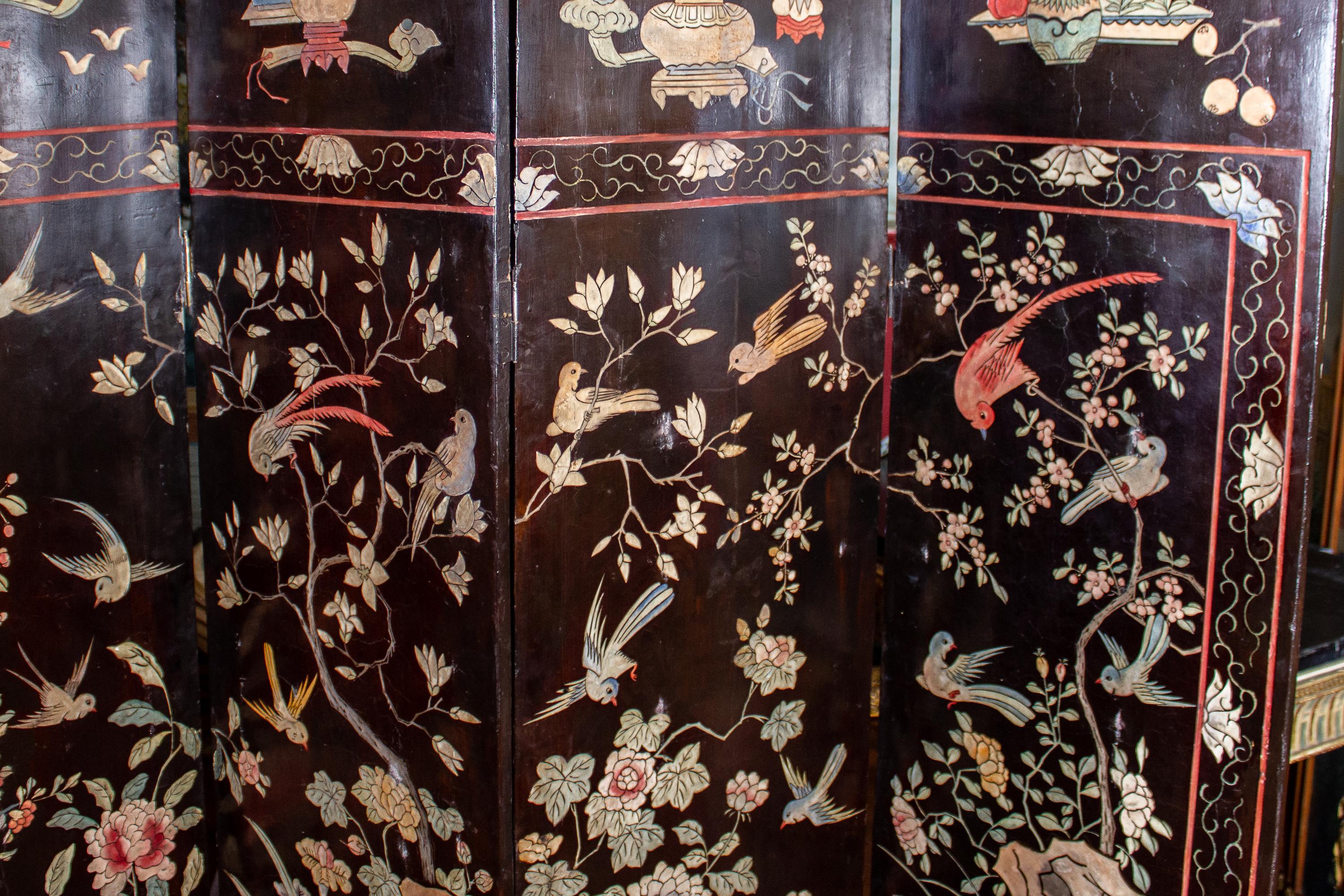 Outstanding double -sided eight dark Coromandel screen is decorated with polychrome landscape, detailed village scenes showing foliage, housing, walkways, and people -engaged in a variety of activities. The screen features a border with foliage,