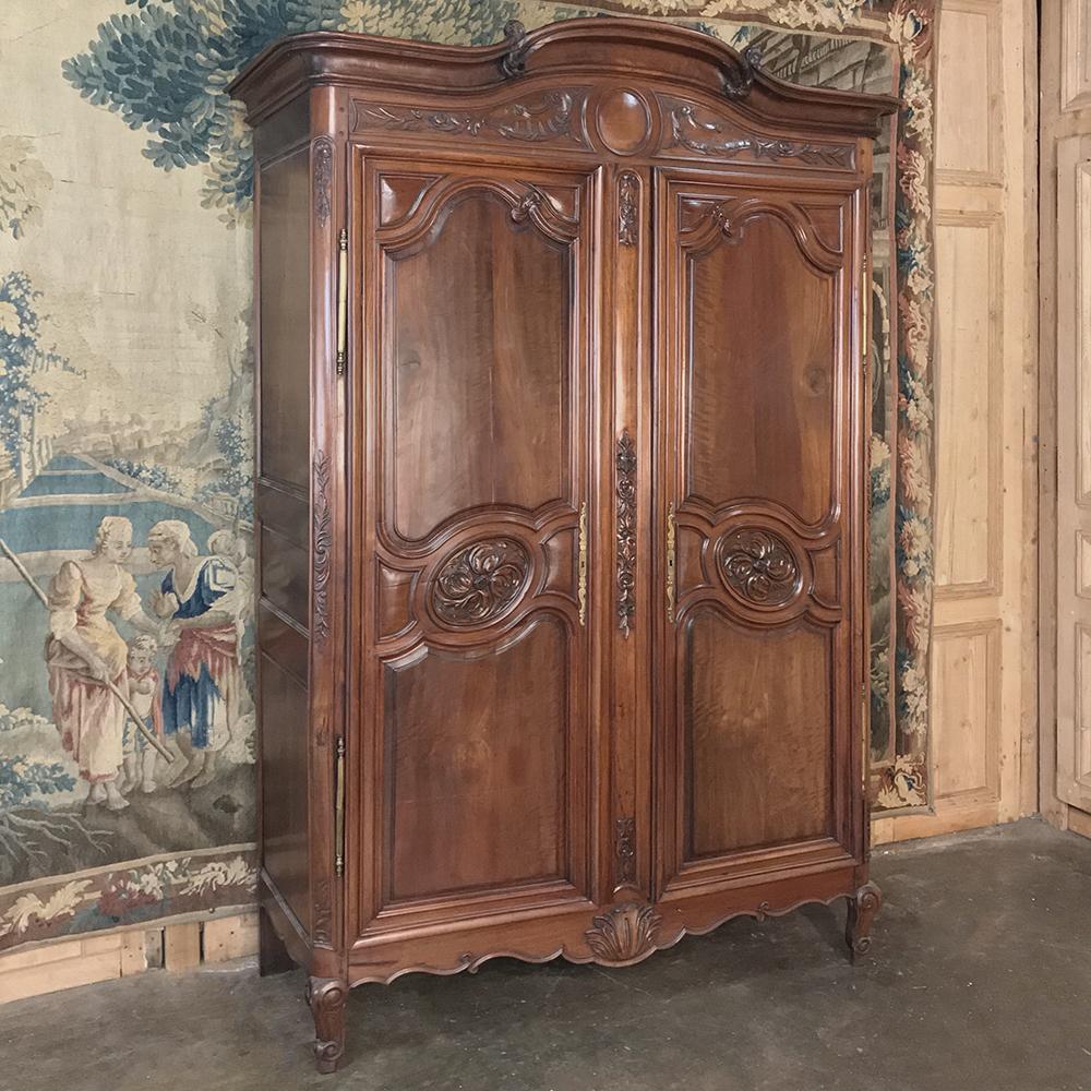 Stunning 19th century Country French solid walnut armoire is a masterwork of the cabinetmaker's art! Talented Lyonaise artisans sculpted the sumptuous French walnut with deft skill designing the case with an artfully scrolled and arched bonnet
