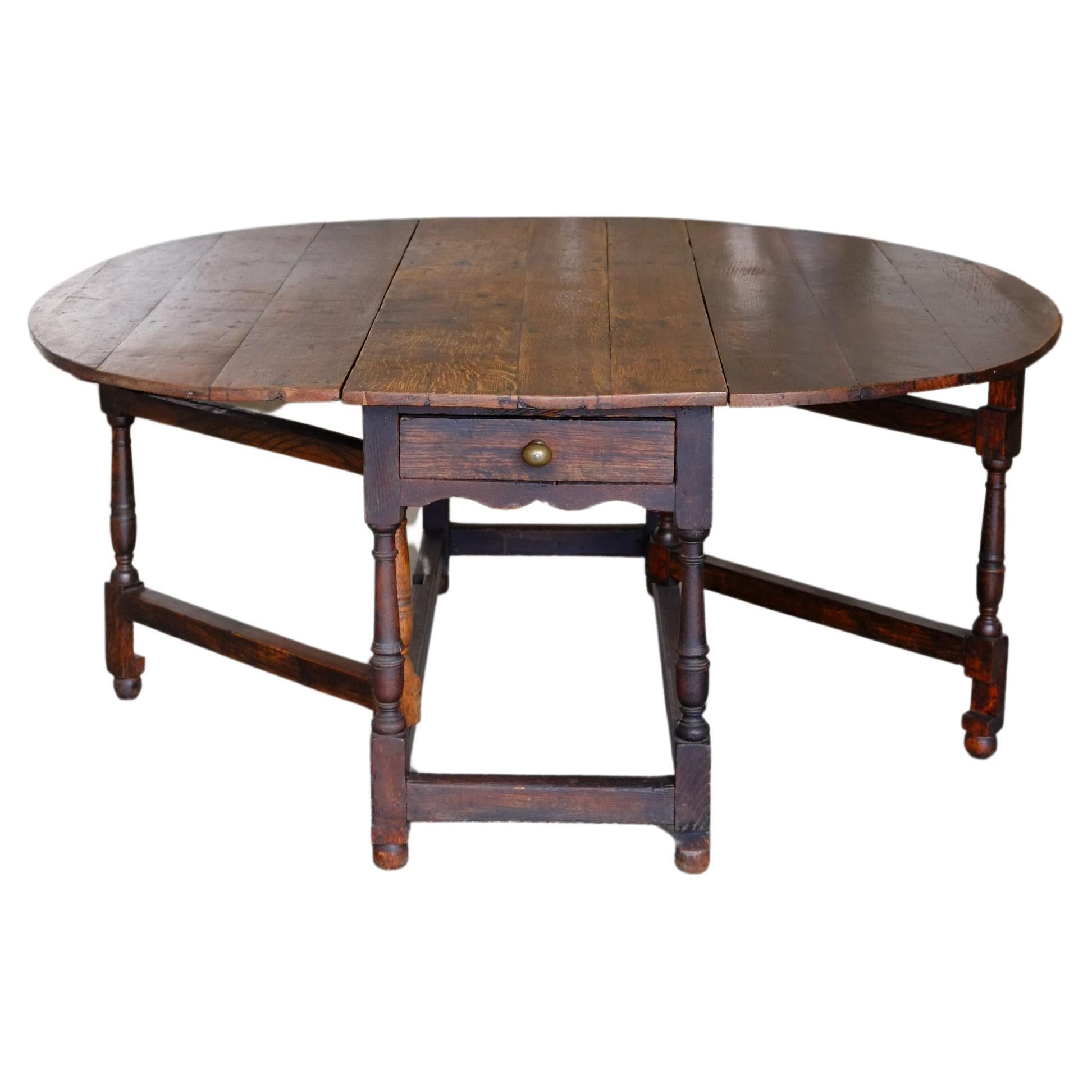 The most beautiful large oval drop leaf table in solid oak. This table has a stunning wide squared off oval shape once it is filly open with a wide solid oak planked top. The table top has a worn rich patina which has been unharmed through time. Two
