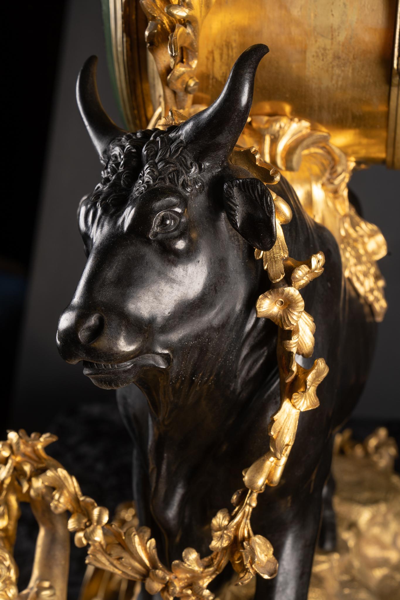 Grande pendule en bronze d'or Louis XV du XIXe siècle, avec taureau en bronze patiné drapé de guirlandes en bronze d'or, représentant le bœuf gras, la dernière viande à être consommée avant le jeûne du carême précédant Pâques. Les chérubins ailés à