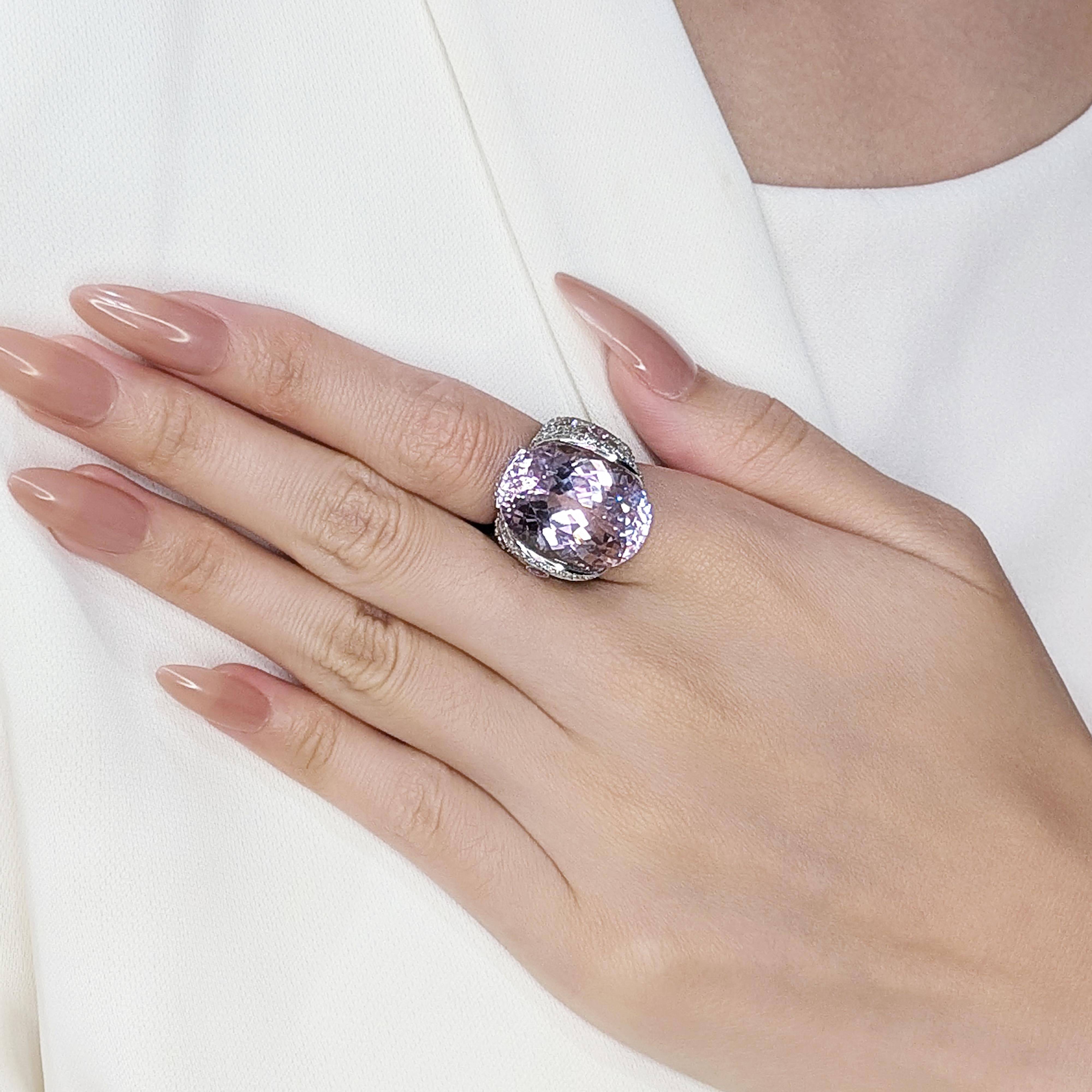This brand-new, unworn ring is a majestic masterpiece, combining grandeur with impeccable craftsmanship. The centerpiece is an impressive 24.45ct oval kunzite, radiating a captivating purple hue that exudes sophistication. Adding to its allure are