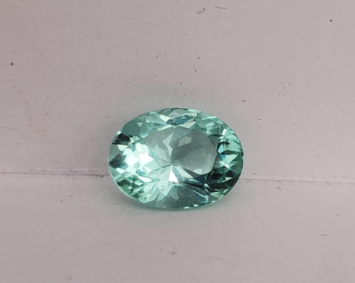 This gorgeous Mozambique Paraiba-type tourmaline weighs 3.21 carats and displays a beautiful neon bluish green color. Photos do not do the glowing aqua color of this gem justice. The mixed brilliant cut oval helps every facet reflect light with