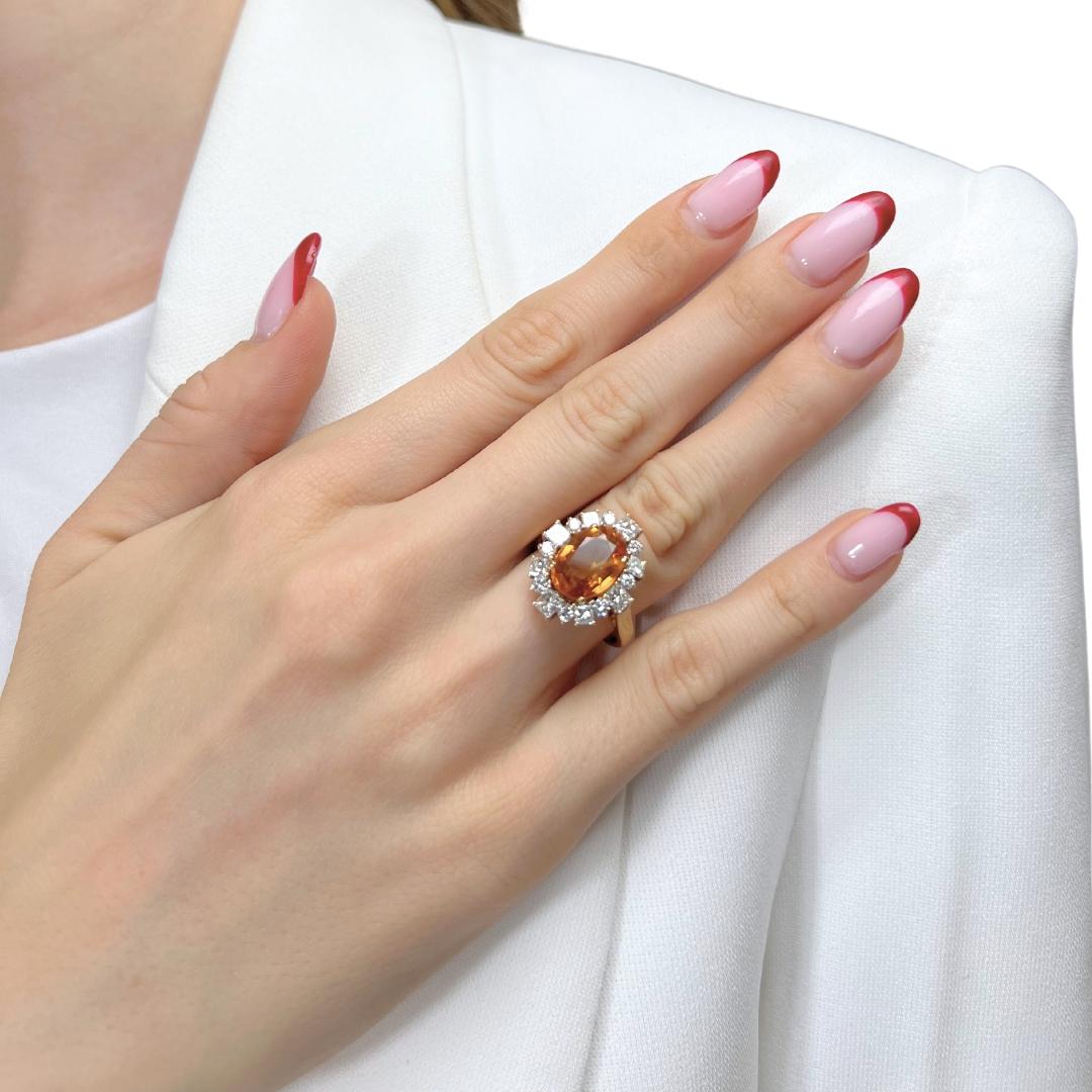 Stunning 6.22ct Gold Sapphire and Diamonds Cluster Ring in 18k Yellow Gold - IGI Certified

This dazzling 18k yellow gold cluster ring showcases a captivating 4.20ct oval orange sapphire at its center, radiating warmth and vibrancy. Accenting the
