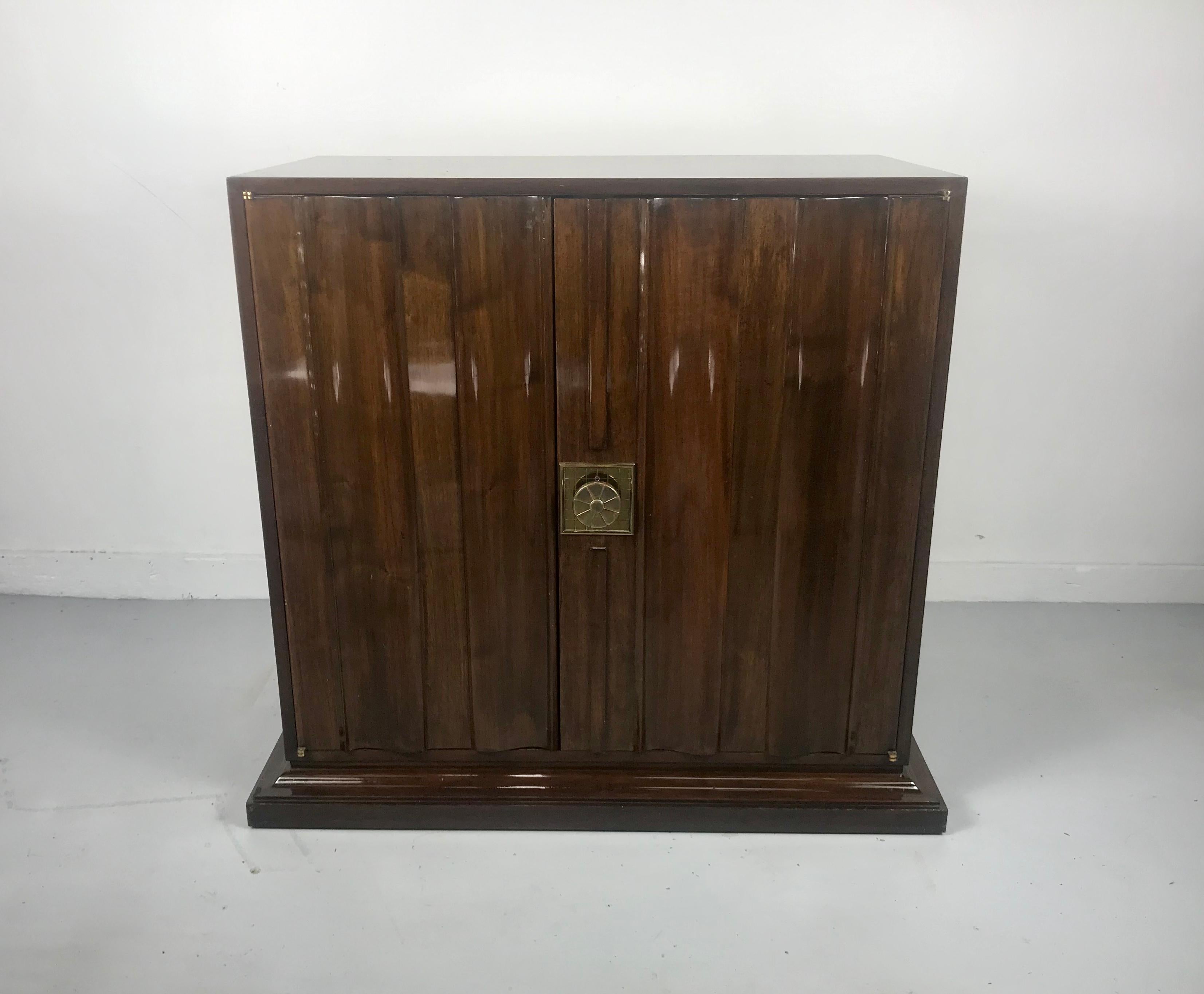 Beautiful two-door stunning fluted walnut cabinet by Tommi Parzinger with Classic cross-hatched brass escutcheons and pulls, with a stepped plinth three-sided base.Hand delivery avail to New York City or anywhere en route from Buffalo NY.