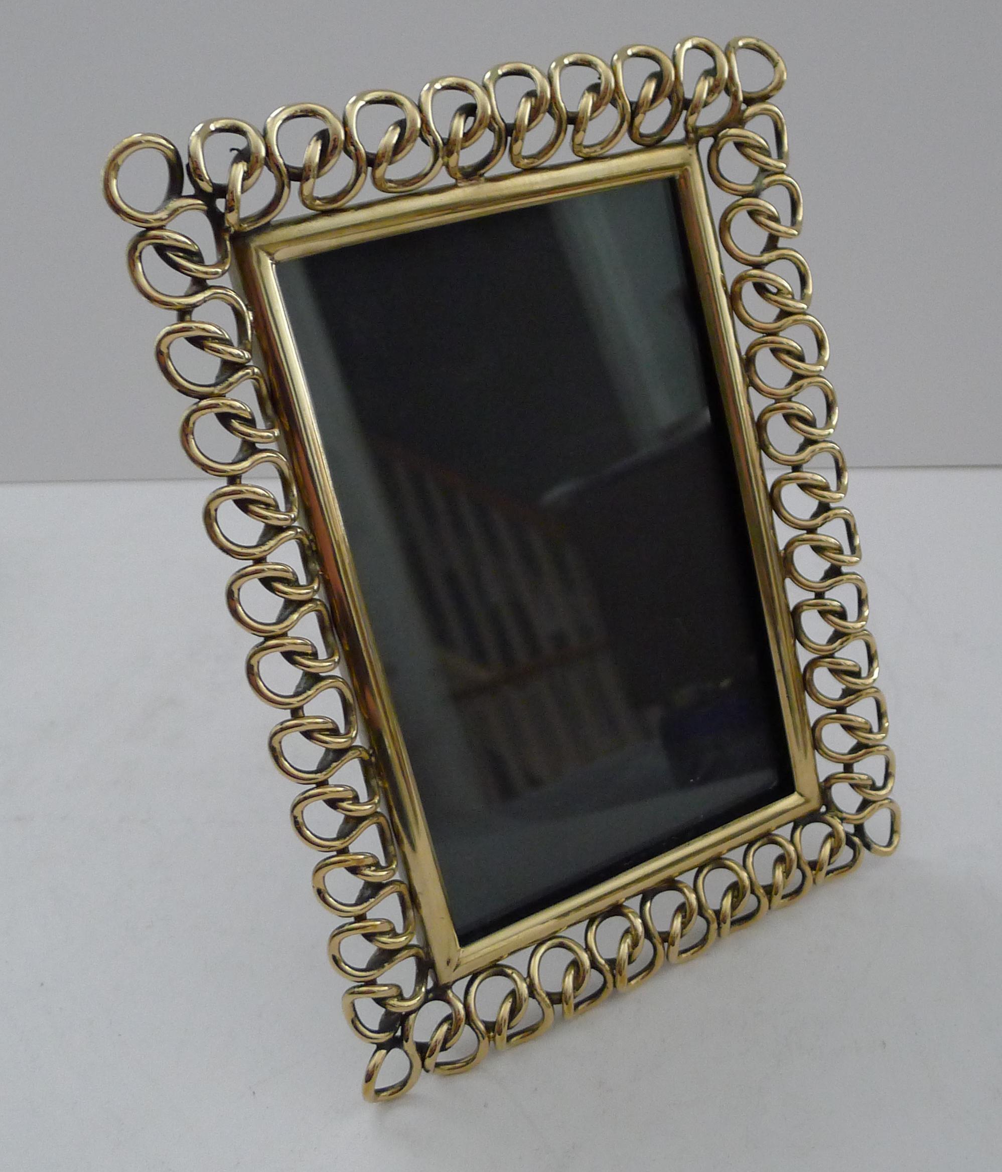 A wonderful, unusual and highly decorative brass ring frame made from heavy cast brass dating to the late Victorian era, c.1890.

The back incorporates the original folding easel stand.

Excellent condition measuring 8 1/2