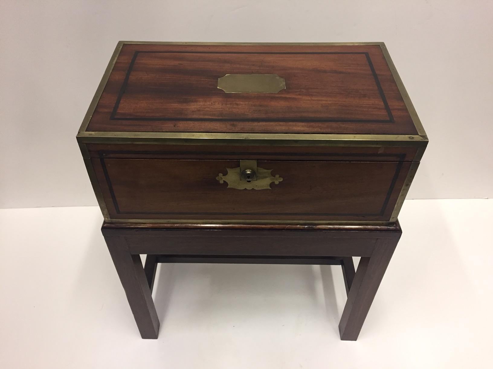 Handsome English 19th century mahogany brass bound lap desk on custom stand makes a rich and functional end or side table with storage space inside.  Surface area of the desk on stand is 21 inches wide by 18 inches deep.