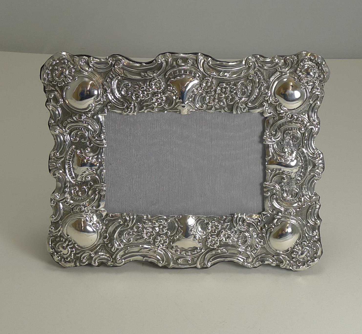 A beautiful English Edwardian photograph frame in sterling silver with exquisite repousse decoration fully hallmarked for Birmingham, 1902. The makers mark is also present for the silversmith, Samuel M Levi.

The backing is made from solid English