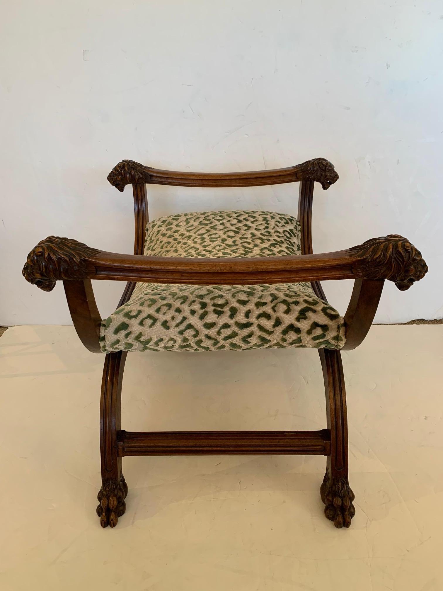 A handsome curved carved walnut bench having marvelous Griffin heads on the side handles and animal paw feet. Upholstery on the seat is an updated cut velvet green and cream animal print.