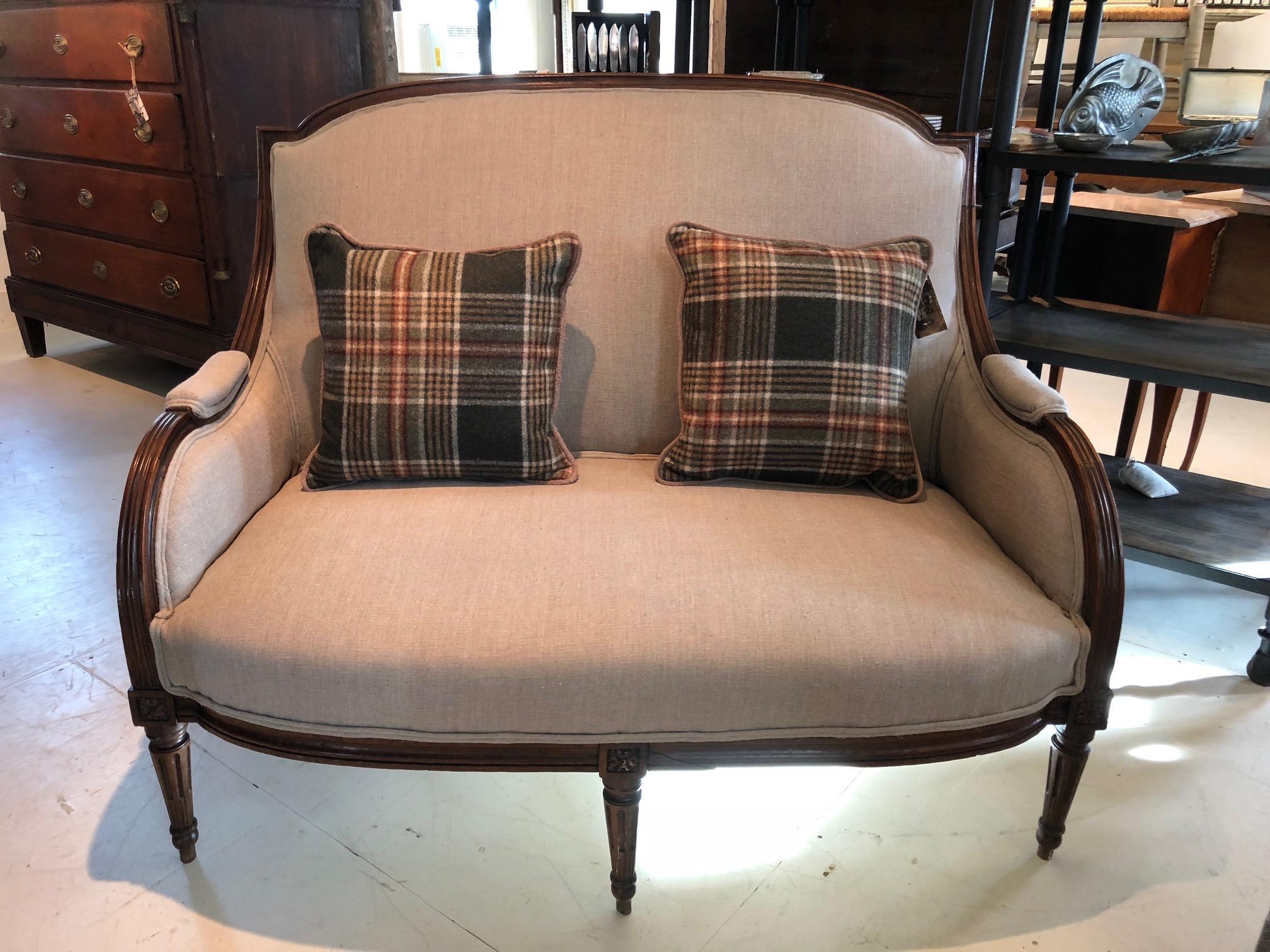Wonderfully shaped French antique loveseat having elegant carved wood frame, curvy arms and fluted legs, newly upholstered in a neutral sand colored linen.
Measures: Arm height 23
Seat height 15.