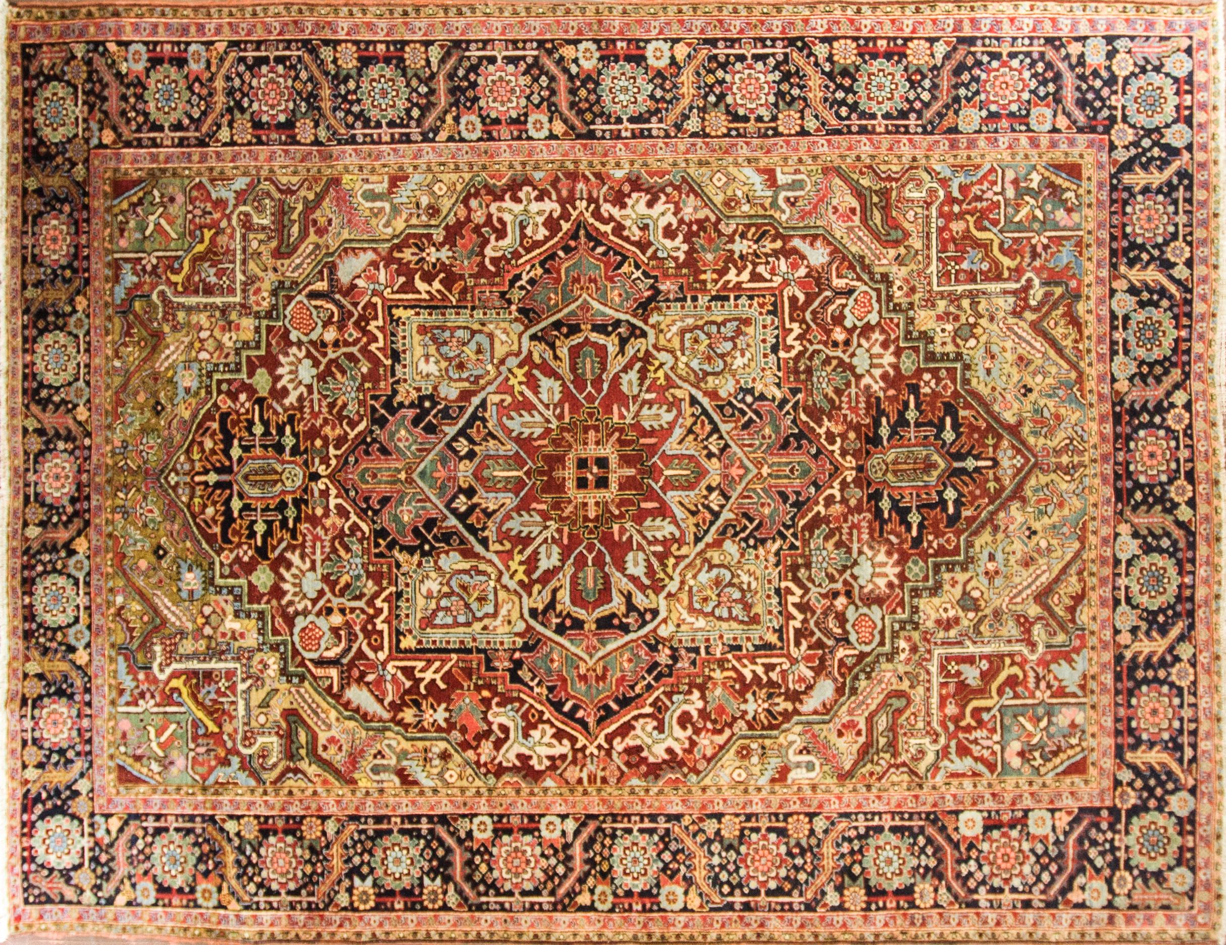 This remarkable and artistic antique rug showcases an ornate, multicolored central design. At the heart of the antique Persian Heriz Serapi rug, a many-petaled flower is surrounded by a 12-pointed stellar shape in light and dark blue. Angular