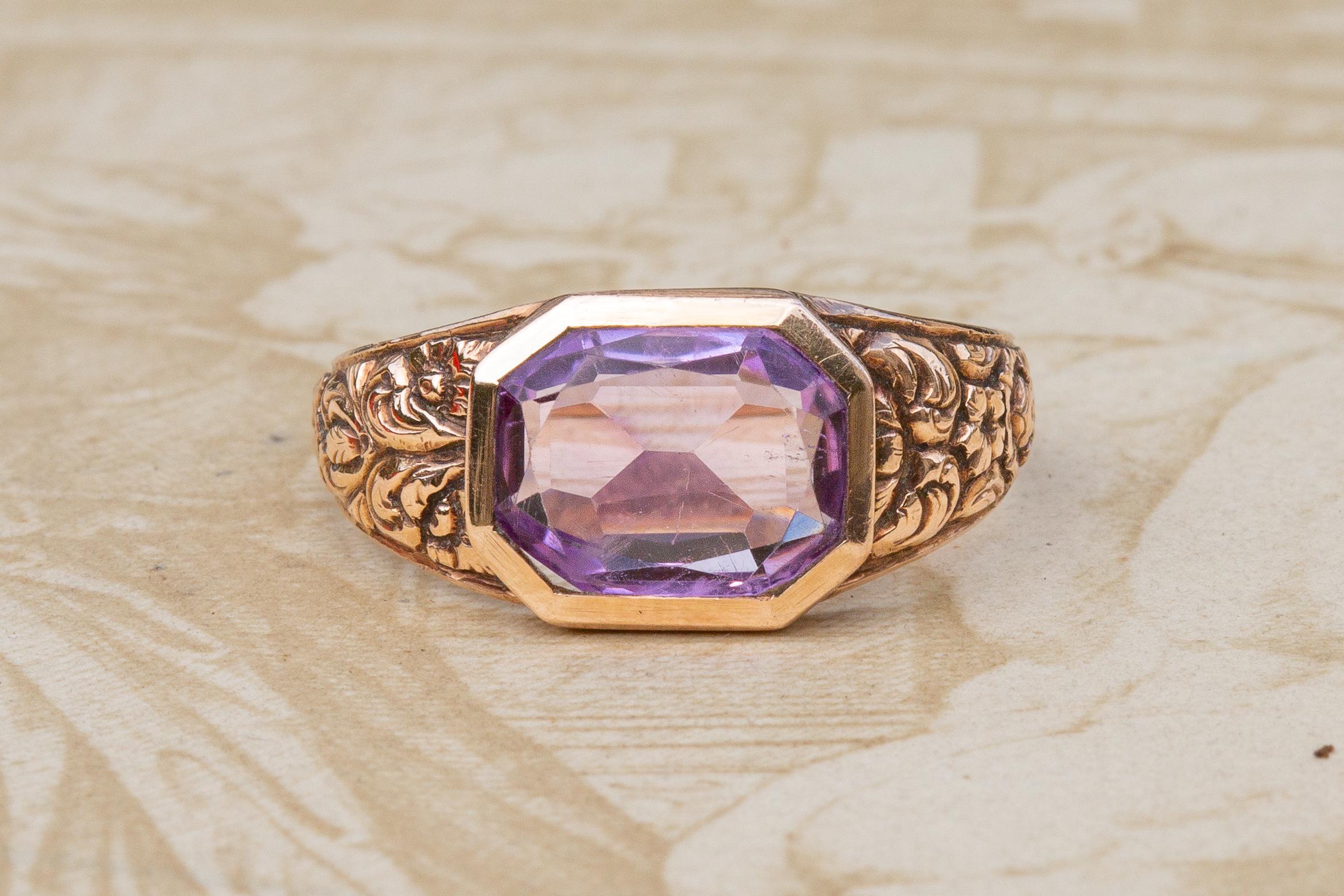 This beautiful, intricate piece dates to the late 19th century, and carries Austrian (Vienna) import hallmarks for 14K gold.  

The ring is set with a gorgeous open-backed 2.5ct ‘Rose de France’ hued amethyst in a raised octagonal bezel setting. The