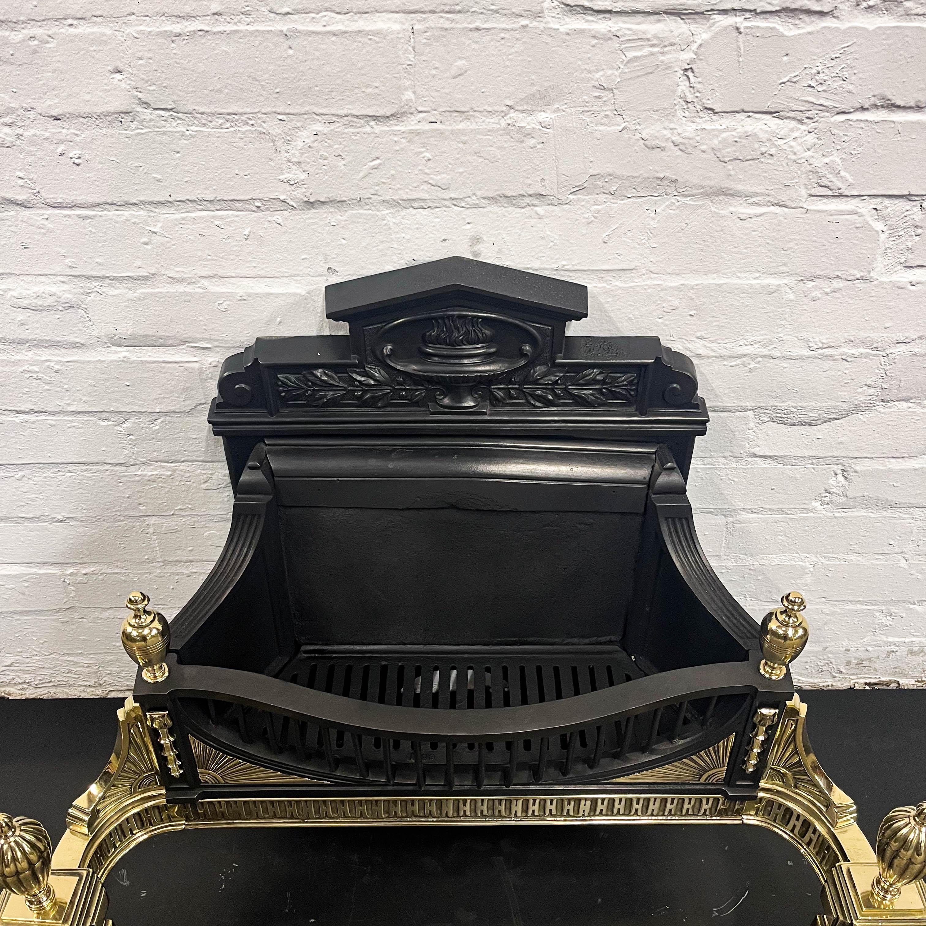 This antique Victorian reclaimed fire basket features classic finials and ornate brass accents throughout. The back of the fire basket is decorated with a cast iron urn and flame motif.

The basket comes complete with an integral cast iron fireback.