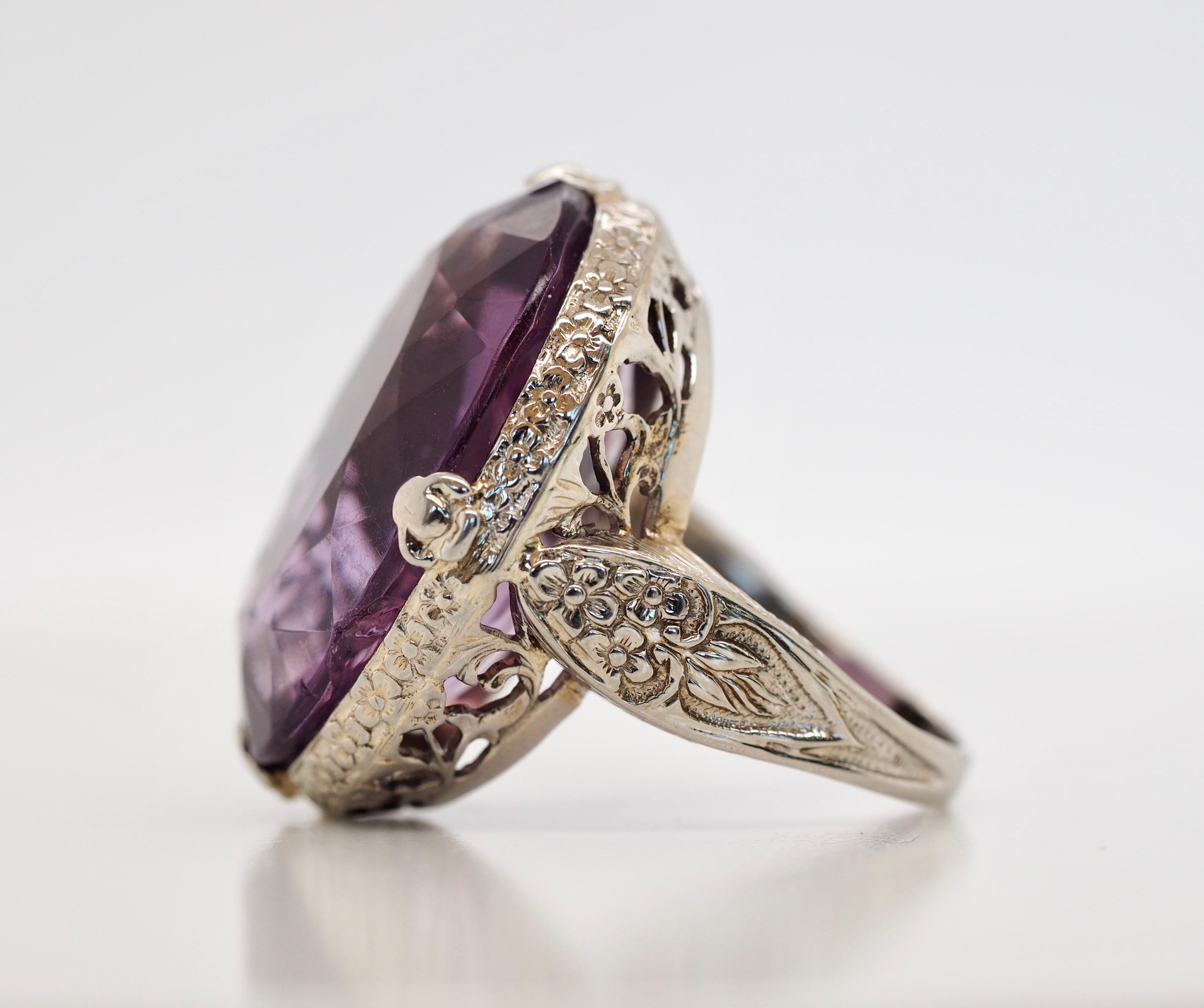 This stunning Art Deco ring is a statement piece that is sure to add grace and beauty to any outfit or vintage collection. The calling card for this ring is an incredible over-sized, natural, oval cut Amethyst stone set in 18K white gold. The stone