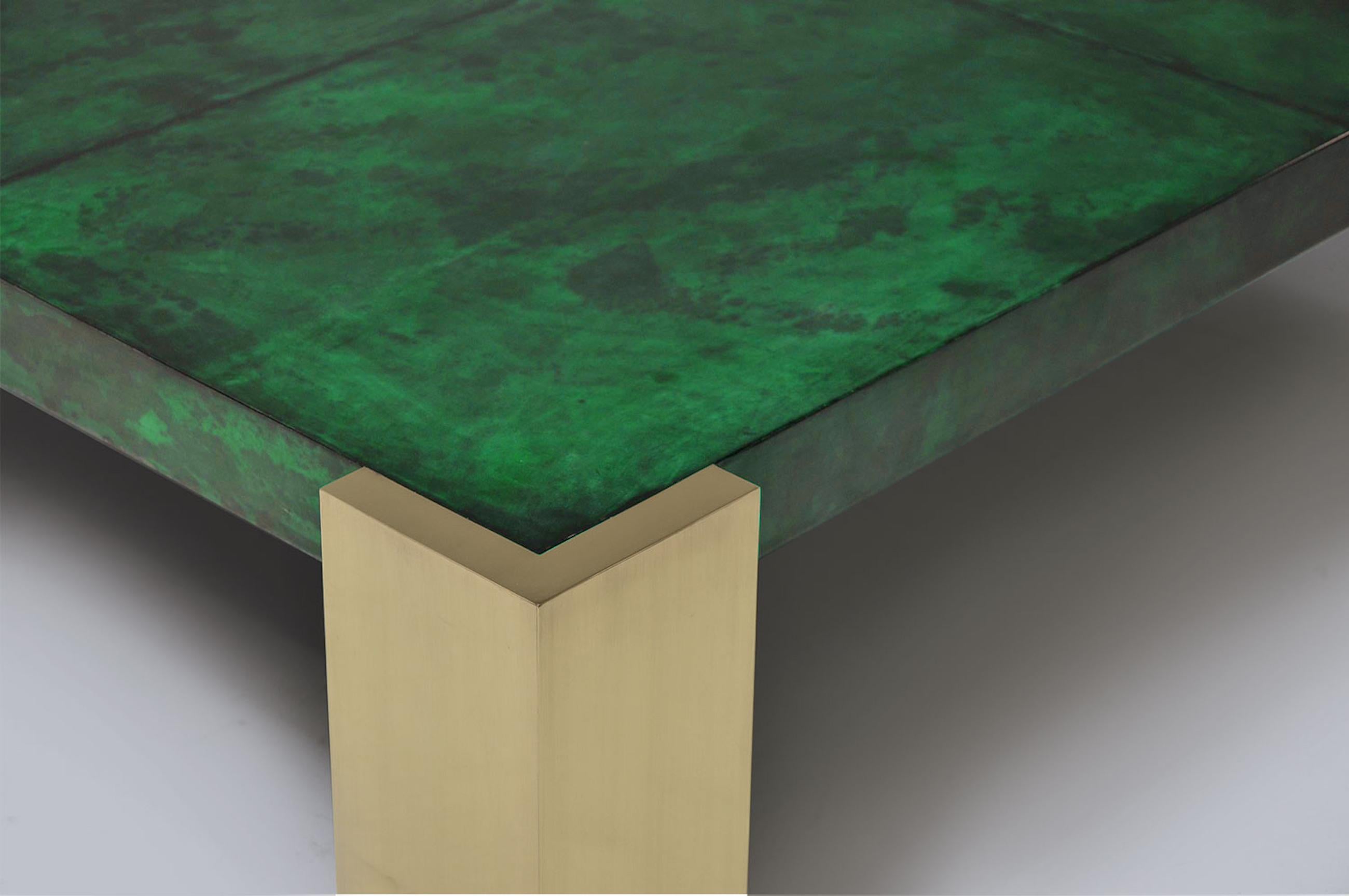 Coffee table in genuine emerald green parchment goatskin leather, sitting on four polished brass feet.
The top is made of several rectangular leather pieces placed side by side. Top is high gloss finished.
The geometric brass bases enhance the