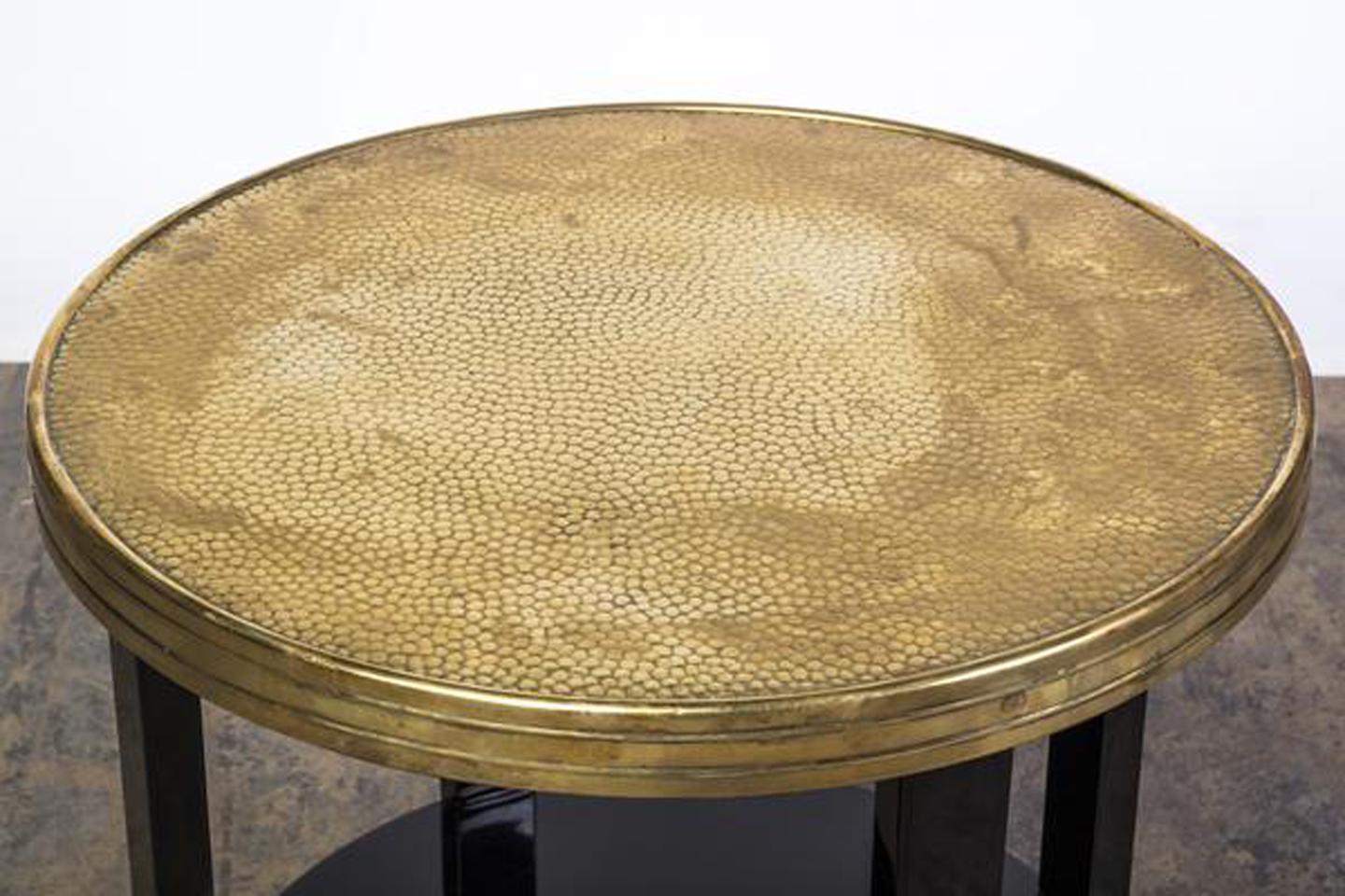 This stunning Art Deco side table features filigree feet finished in a high gloss black lacquer with a circular form design and captivating embossed brass top plate.

Made in Germany, circa 1930.