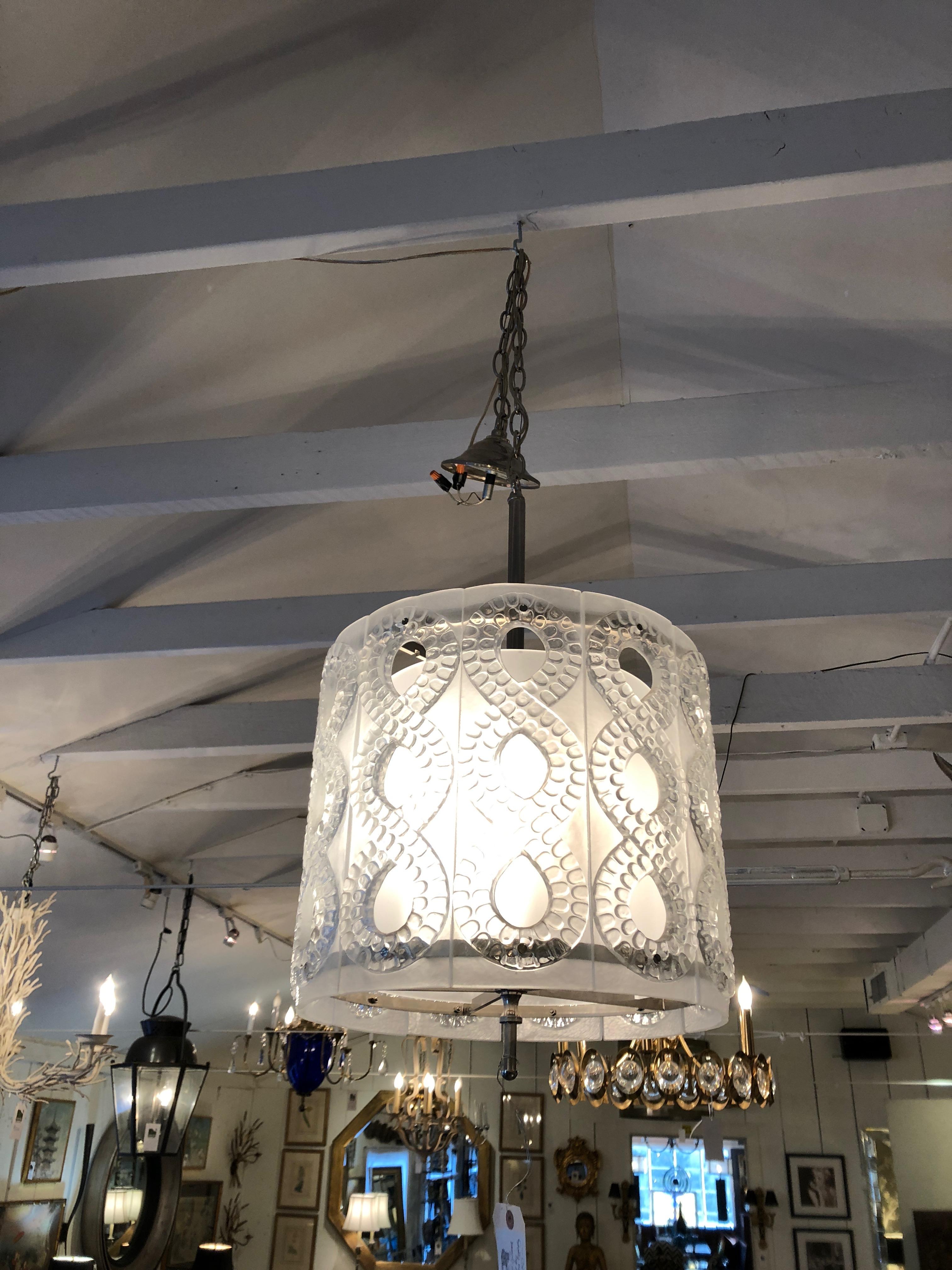 Gorgeous contemporary light fixture having a 15 inch diameter cylindrical shape with chunky frosted glass panels decorated with figure 8s of patterned glass, all encasing a second layer of interior glass. Nickel finial, bar and chain and ceiling