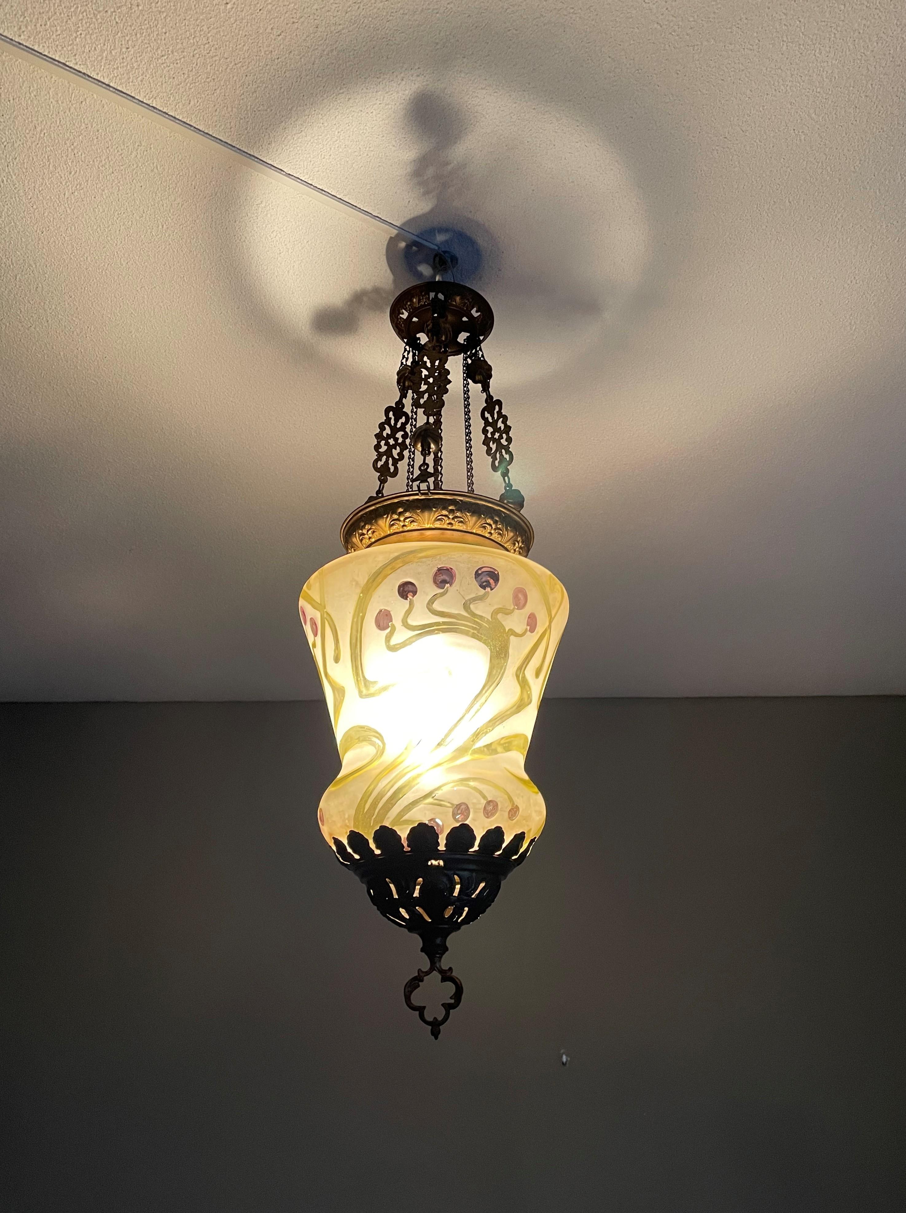 Graceful and all handcrafted antique light fixture.

This early Arts & Crafts pendant has an aesthetic beauty that you don't find anymore in this day and age. It has the most pleasing to the eye shape and colors and the handcrafted brass has a