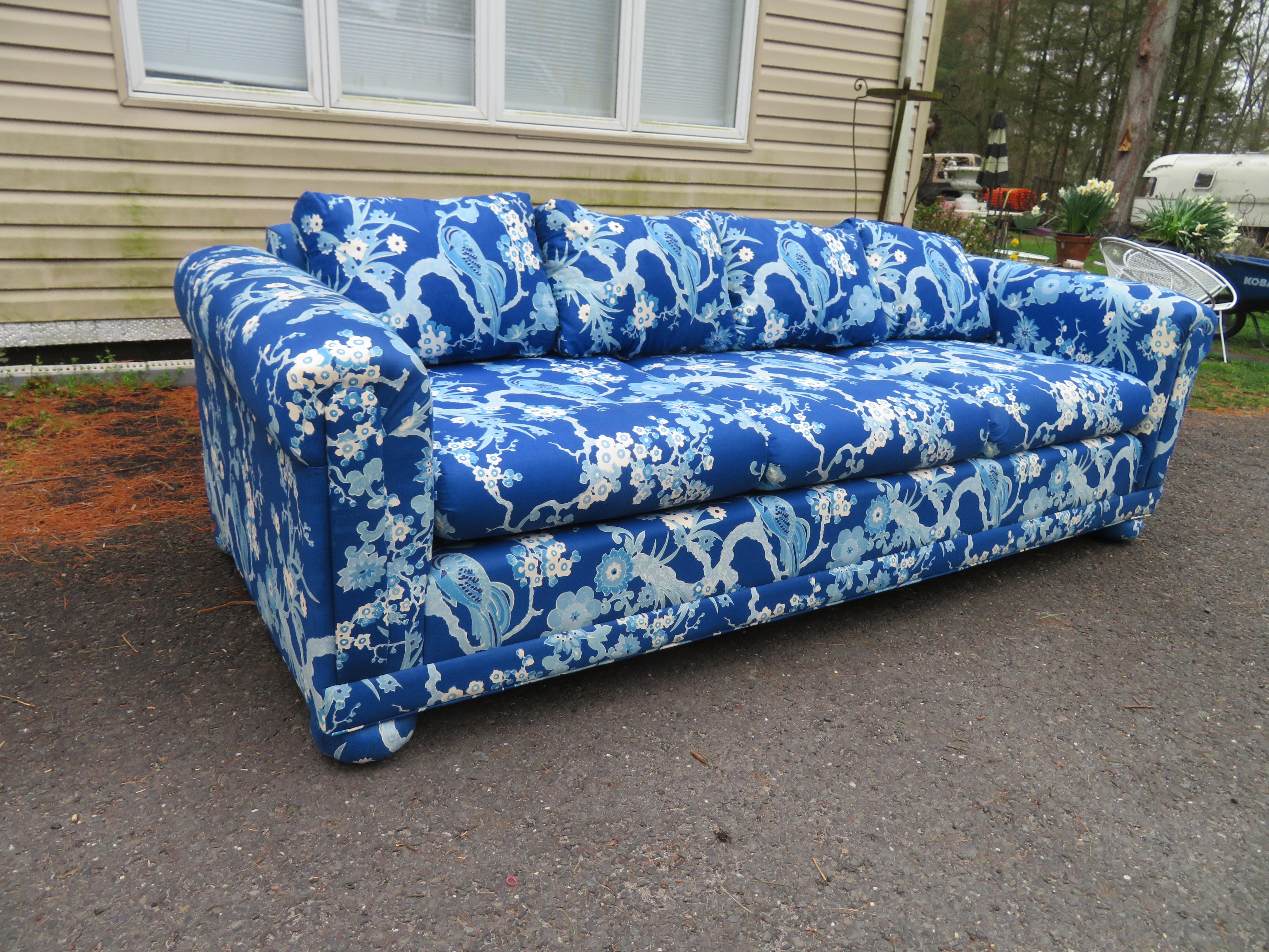 Stunning Chinoiserie style upholstered sofa with fabulous vintage bird of paradise floral fabric. This stylish sofa is actually all the rage right now and is in remarkable vintage condition. We just love the bold blue and white Chinoiserie fabric