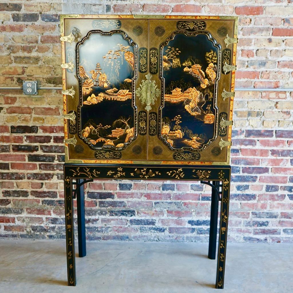 Simply stunning, ornate (inside and out), George III Oriental lacquer cabinet by Baker Furniture. It features two panelled black lacquer doors and sides elaborately decorated in a raised gilt and ochre landscape design. It has finely cast brass