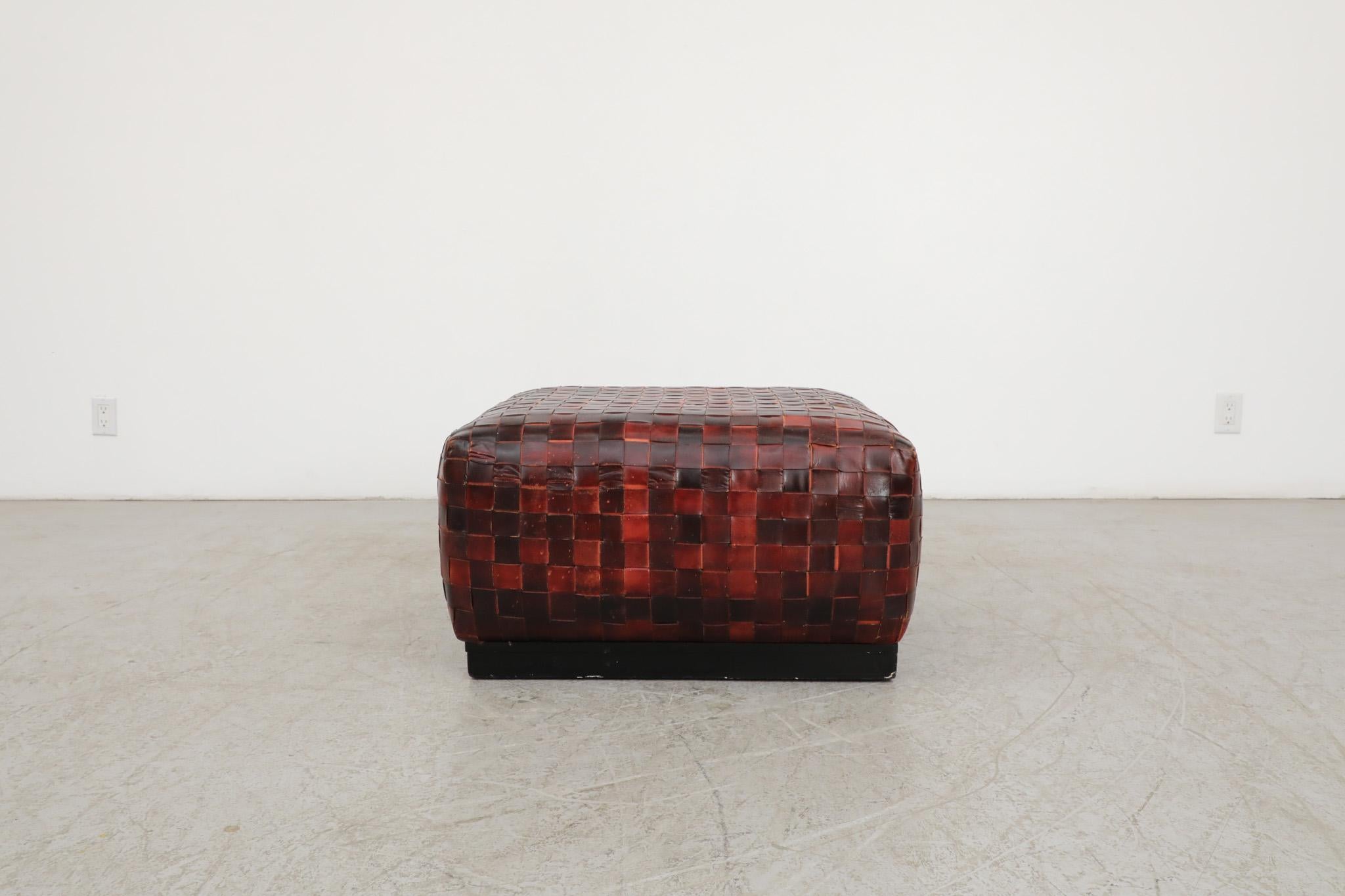 Stylish and eye catching, De Sede style ottoman or coffee table with thick, red dyed basket woven leather and a black wood framed base. Manufactured in The Netherlands in the 1990's. In original condition with wear and patina consistent with its age