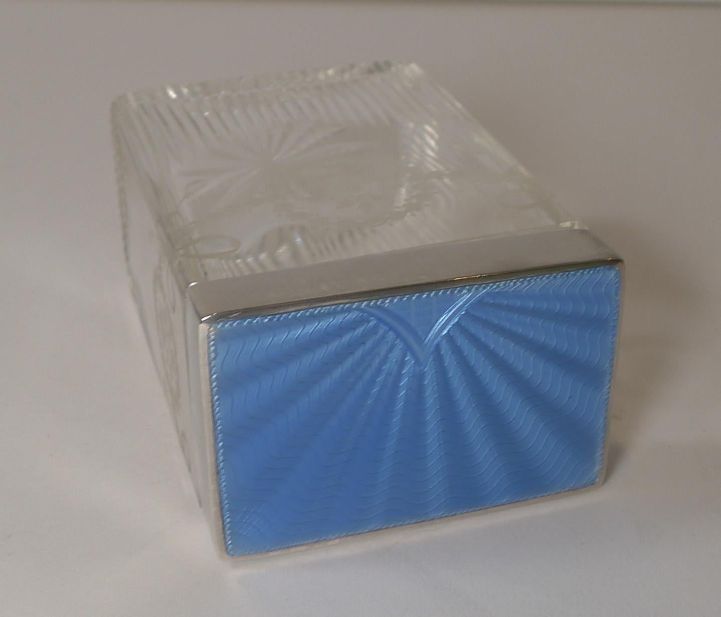 A truly stunning Art Deco glass and sterling silver vanity jar or box, the top decorated with a lovely blue guilloche enamel with a bright patina showcasing the highly decorative Art Deco design below.

The glass is exquisite with fine channel