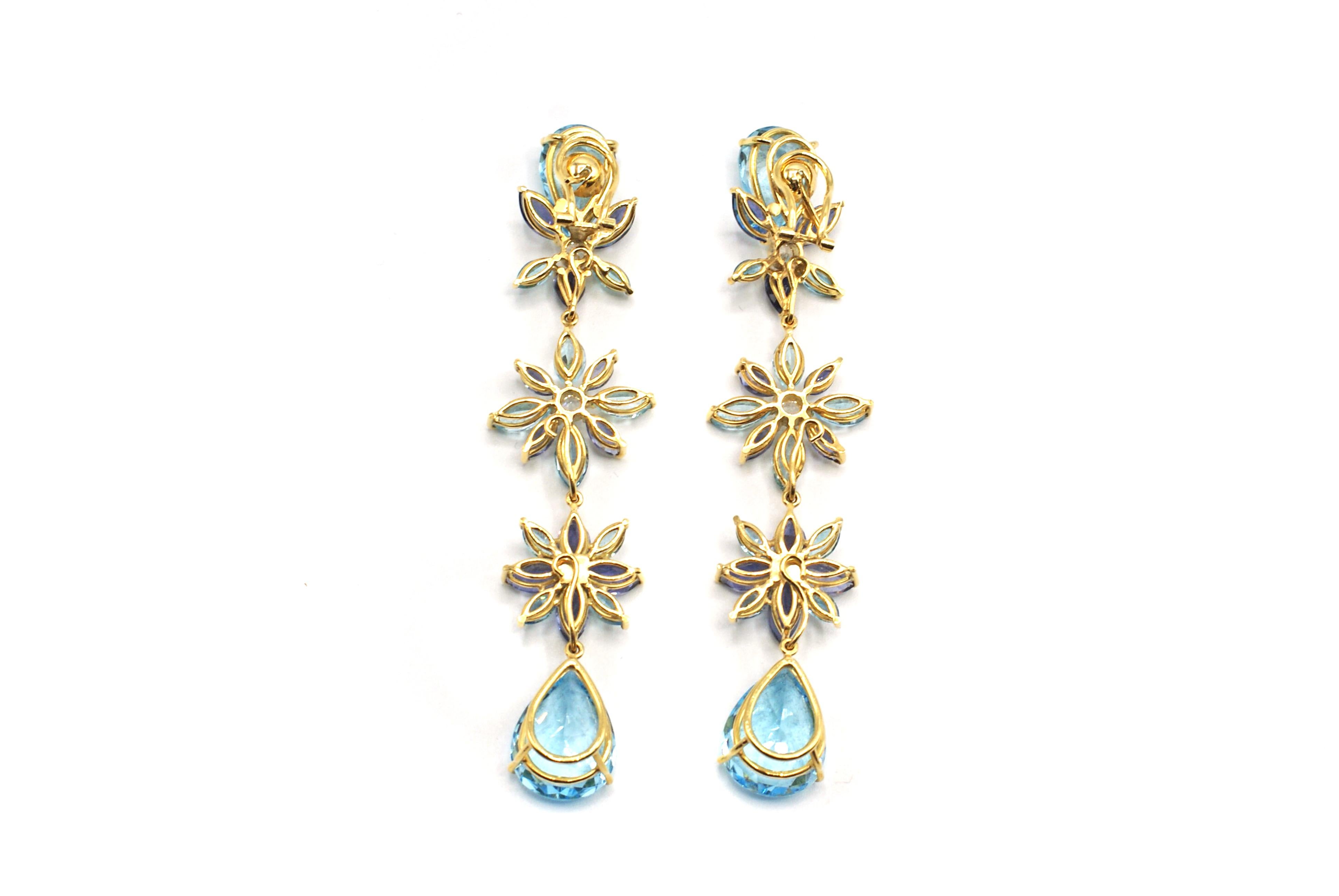 These stunning and bold 18 karat yellow gold earrings extend 3.5 inches from the earlobe down the neck, insuring to catch the eye of everyone in the room. Finely hand-crafted each earring is set with 2 pear shape vibrant blue Topazes on the top and