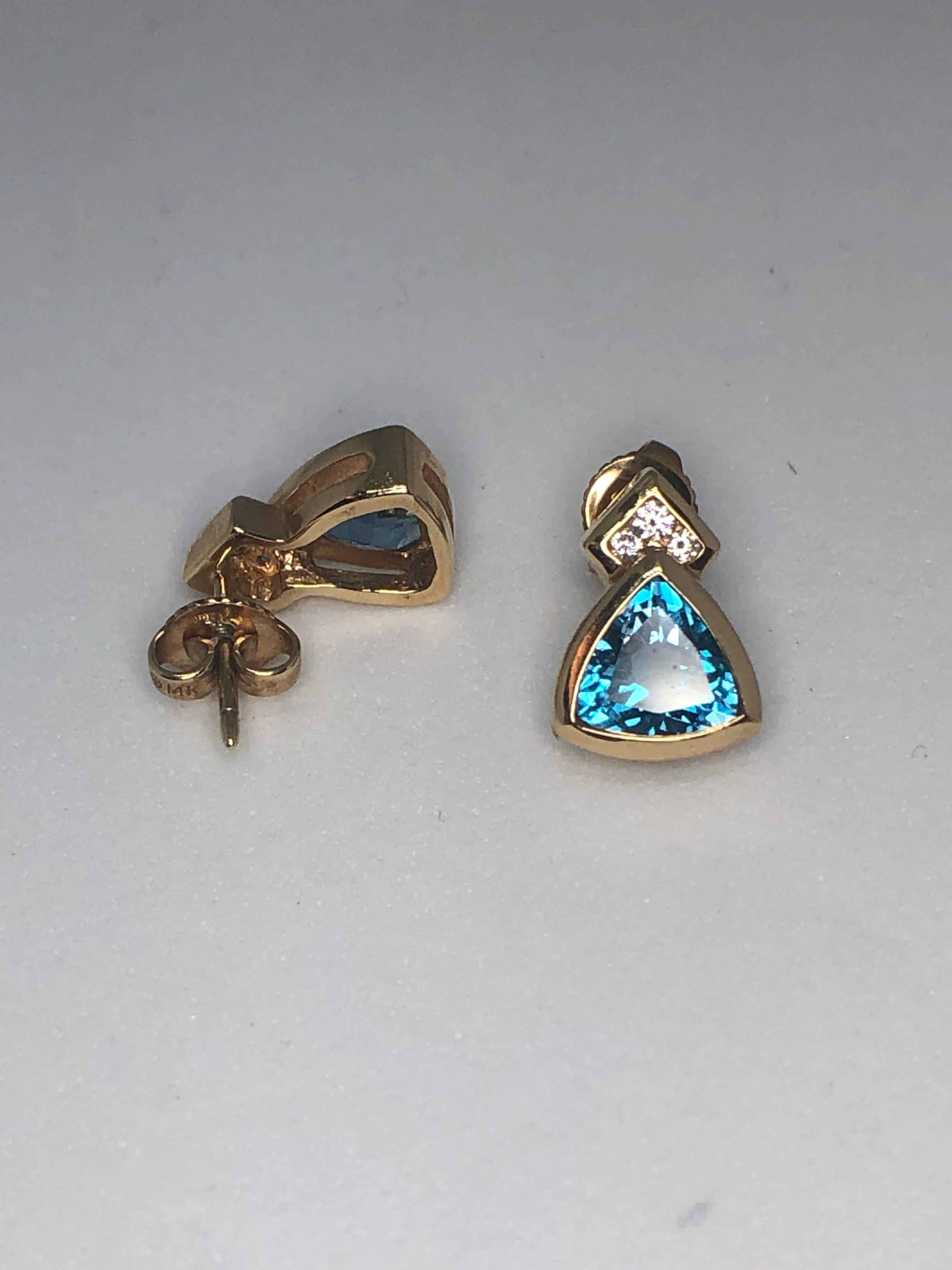 Lady's blue topaz and diamond earrings by Church & Company in 14kt yellow gold. These earrings boast of 2 - blue topaz gems = 1.99ct total weight, accented by 6 - full cut round diamonds = .11ct total weight.