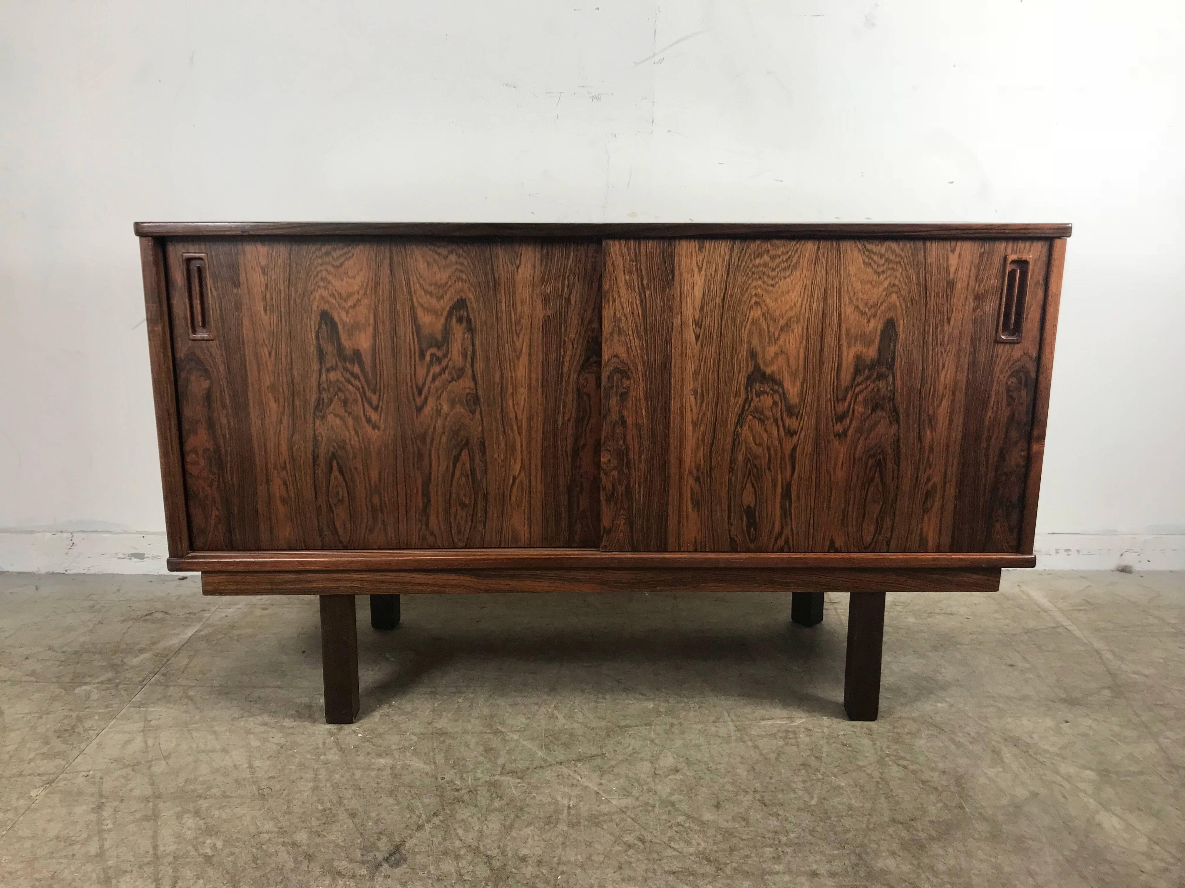 Stunning bookmatch rosewood credenza, cabinet by Drylund Denmark. Handsome cabinet with two sliding doors, shelf and drawer, simple, elegant design with stunning richly grained rosewood veneer, hand delivery avail to New York City or anywhere en