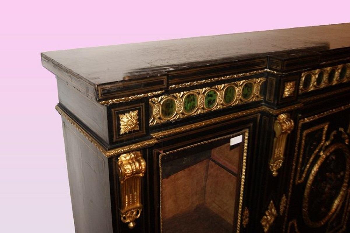 Large and spectacular French sideboard from the first half of the 1800s, in Boulle style, made of ebonized wood. It features 2 glass-fronted doors, 1 closed door, rich bronze appliques, and semi-precious hard stone inlays with a green-tinged