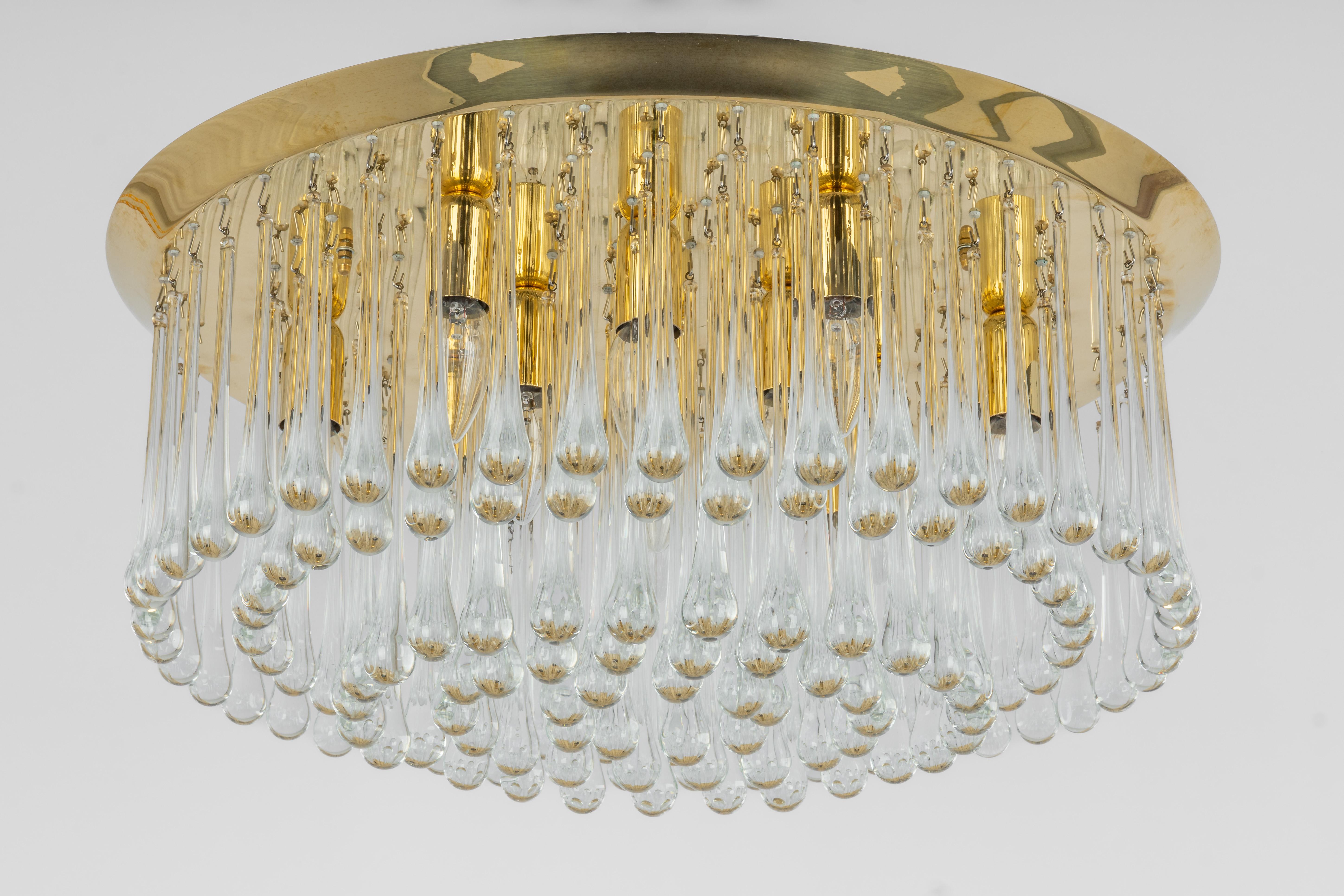 A wonderful gilt brass light fixture comprises many crystal teardrop glass pieces on a brass frame. Its made by Kalmar (Serie: Tropfen), Austria, manufactured, circa 1970-1979.

It needs 13 small bulbs (E-14 , 40 W for each bulb)
Light bulbs are