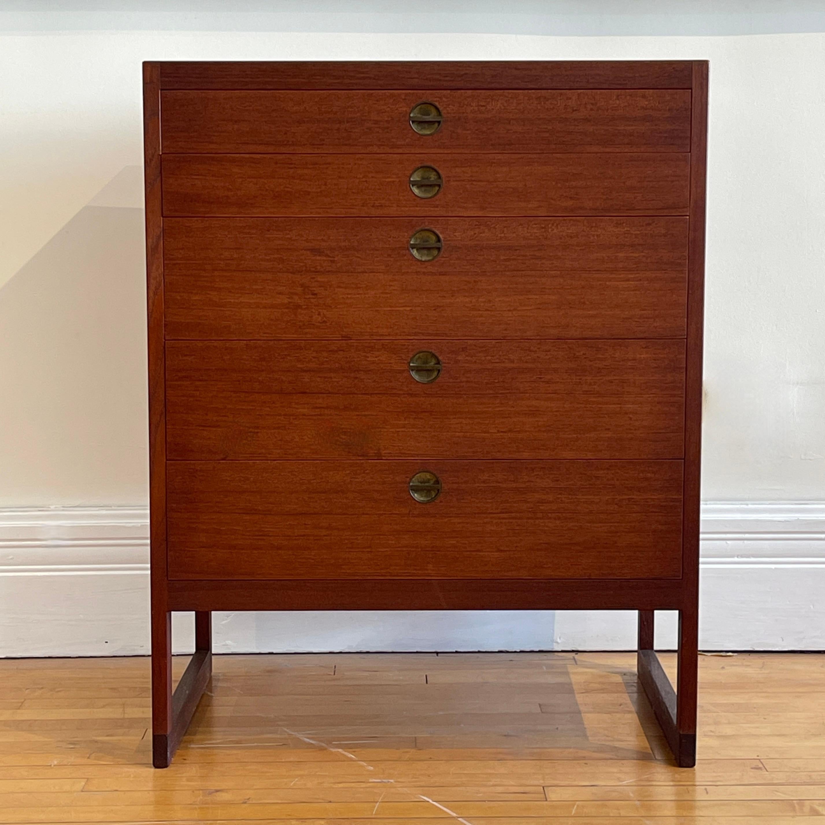 A mid century Danish modern chest of drawers designed by Børge Megensen for cabinetmaker Povl Dinesen of Copenhagen, Denmark. Teak wood construction with two shallow drawers over three deeper drawers, all with lovely sculptural inset brass pulls,