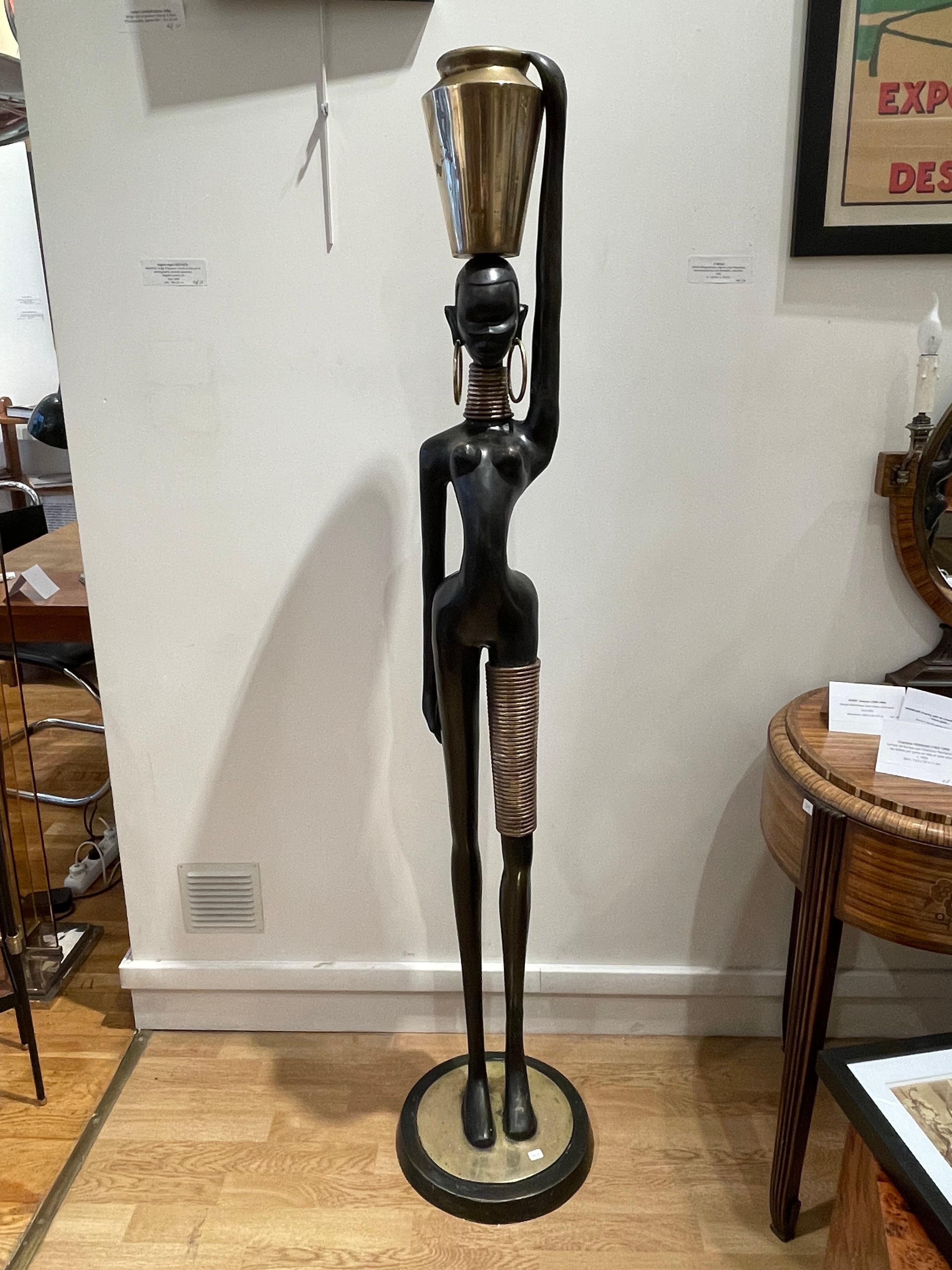 Stunning Bronze of an African lady carrying water,  in the style of Karl Hagenauer (1898-1956), 1970’s, Bronze with double black and gilt patina, pierced for electrification
Dimensions : 163.5 cm / 64,37 inches
Stunning life-size bronze sculpture of