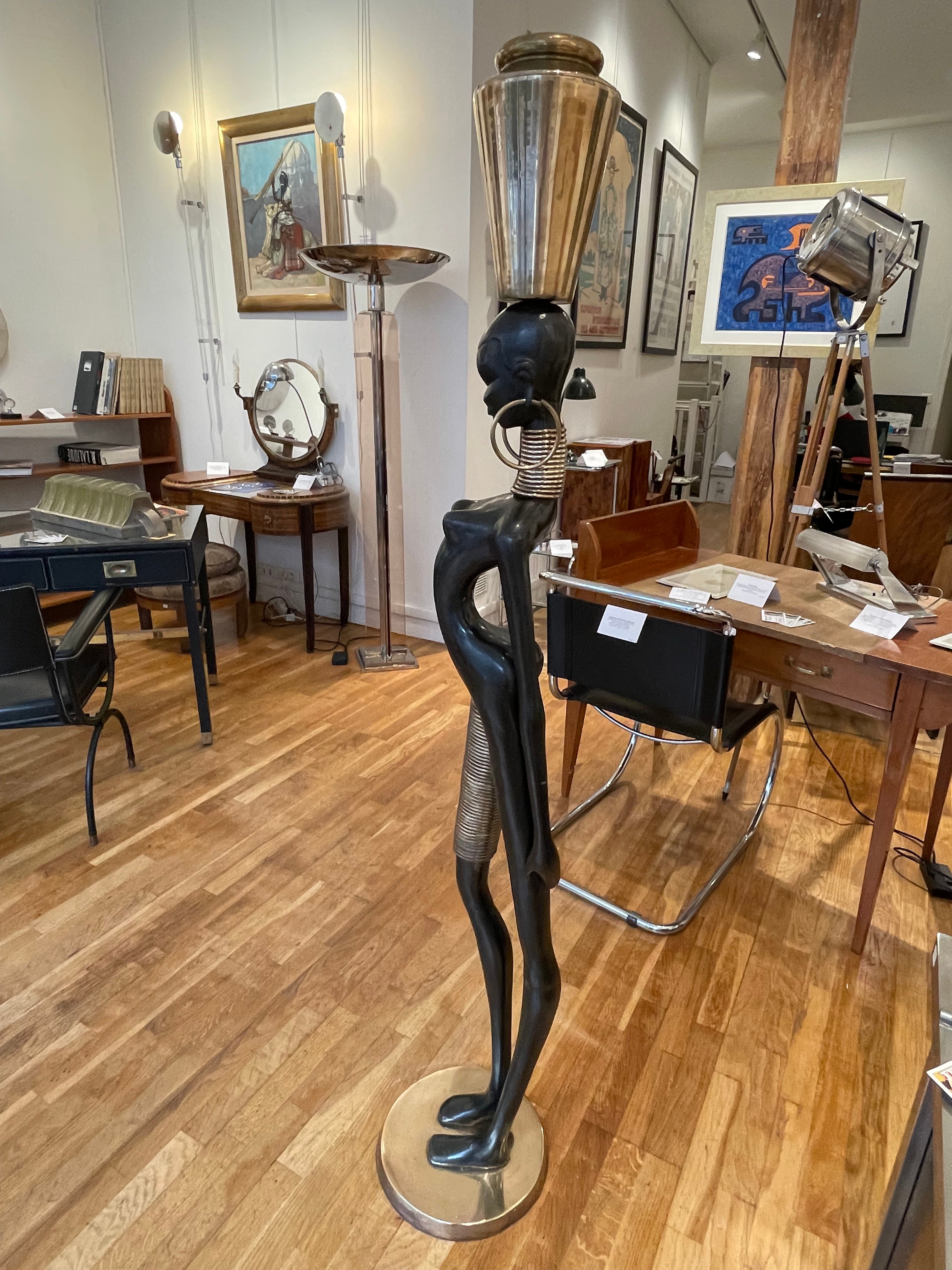 Stunning life size bronze of an African lady carrying water. Bronze and brass. It is in the typical style of Karl Hagenauer; famous Austrian designer active between the 1920's and the 1950's.
Size: height 166cm, diameter of the base 30cm.