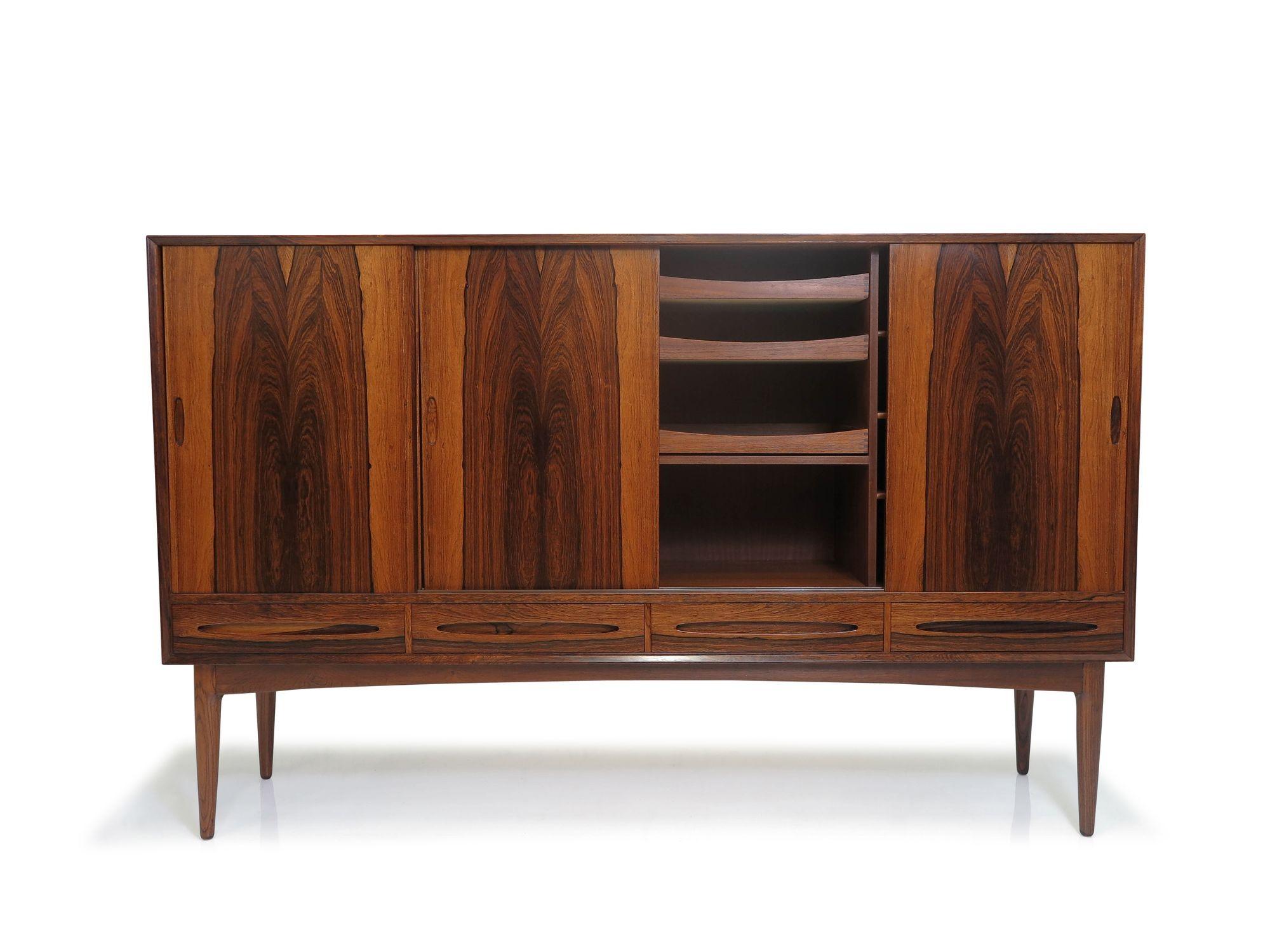 1950's Bruno Hansen Brazilian Rosewood credenza finely crafted with dramatic book-matched grain across four sliding doors each with sculpted and recessed pulls, over four drawers. The doors open to reveal a Cuban mahogany interior with an