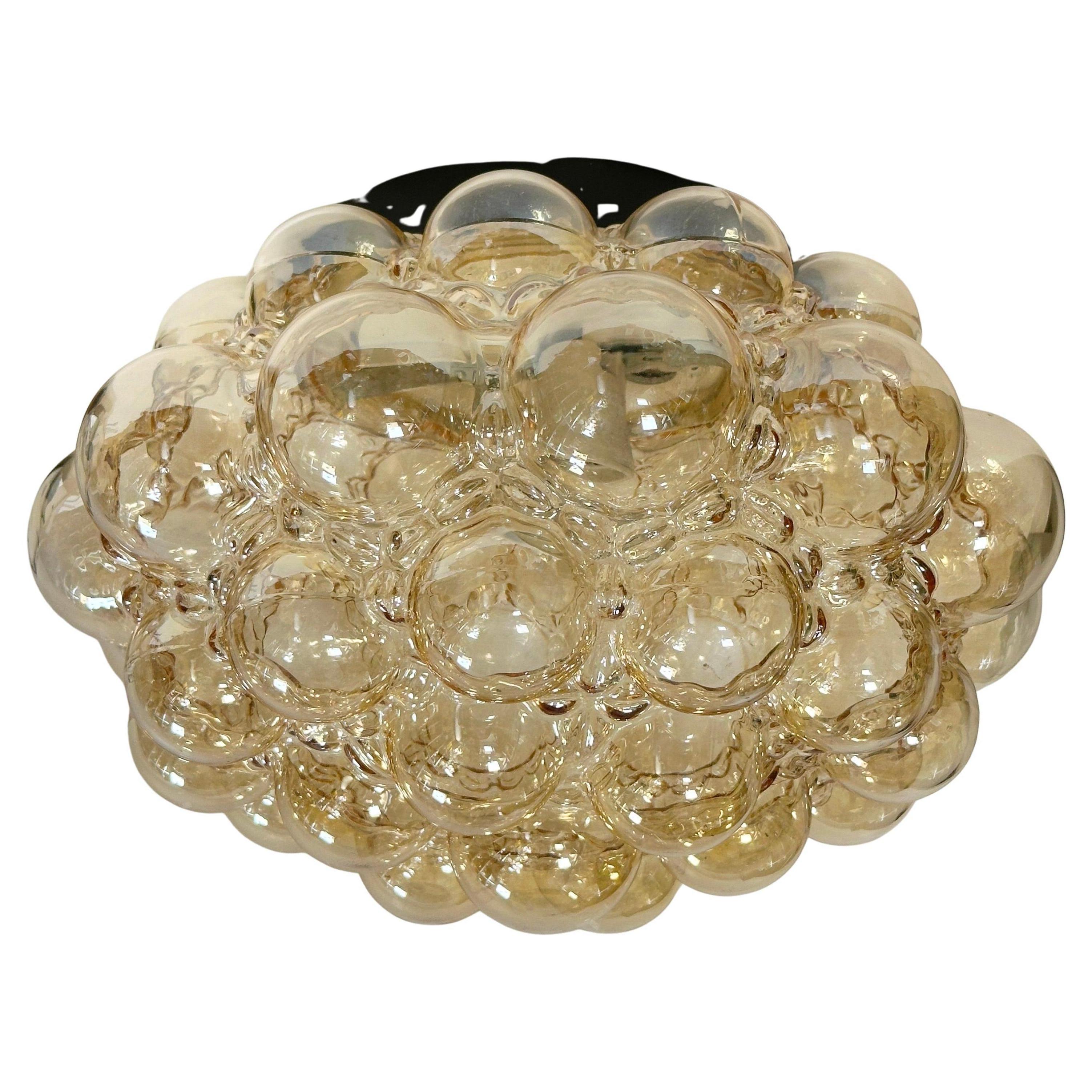 A beautiful and rare midcentury amber glass ceiling light designed by Helena Tynell for Glashuette Limburg (Germany, 1960s). The amber or champagne colored hand blown bubble glass shade casts a wonderful light (see image). A Mid-Century Modern