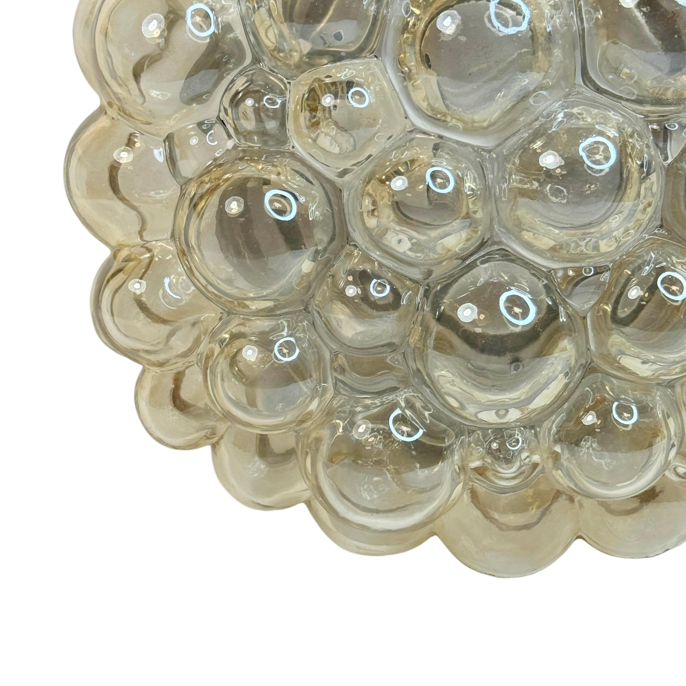A beautiful and rare midcentury amber glass ceiling light designed by Helena Tynell for Glashuette Limburg (Germany, 1960s). The amber or champagne colored hand blown bubble glass shade casts a wonderful light. A Mid-Century Modern design Classic.