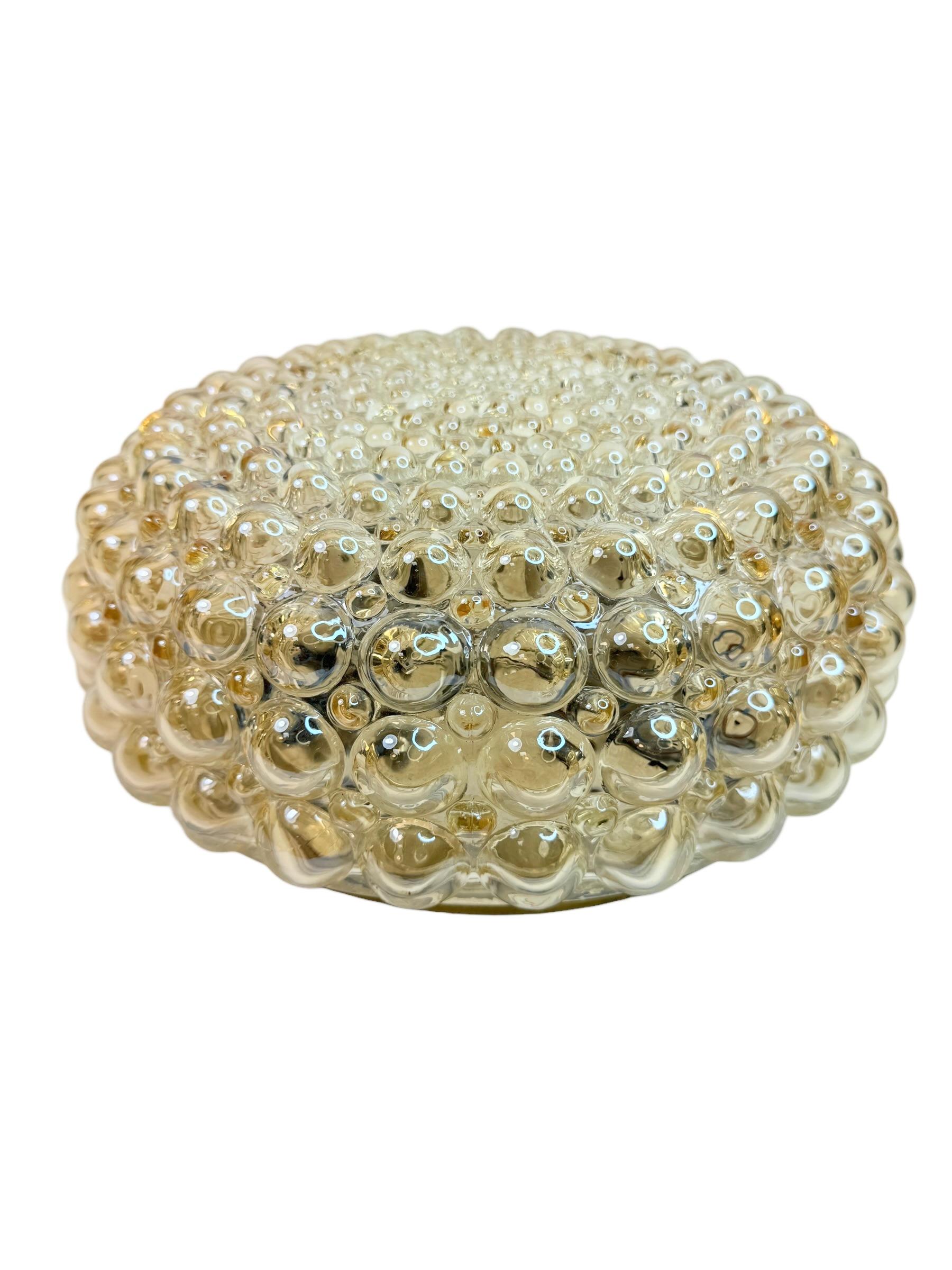 A beautiful and rare midcentury amber glass ceiling light designed in the style of Helena Tynell for Glashuette Limburg (Germany, 1970s). The amber or champagne colored hand blown bubble glass shade casts a wonderful light. A Mid-Century Modern