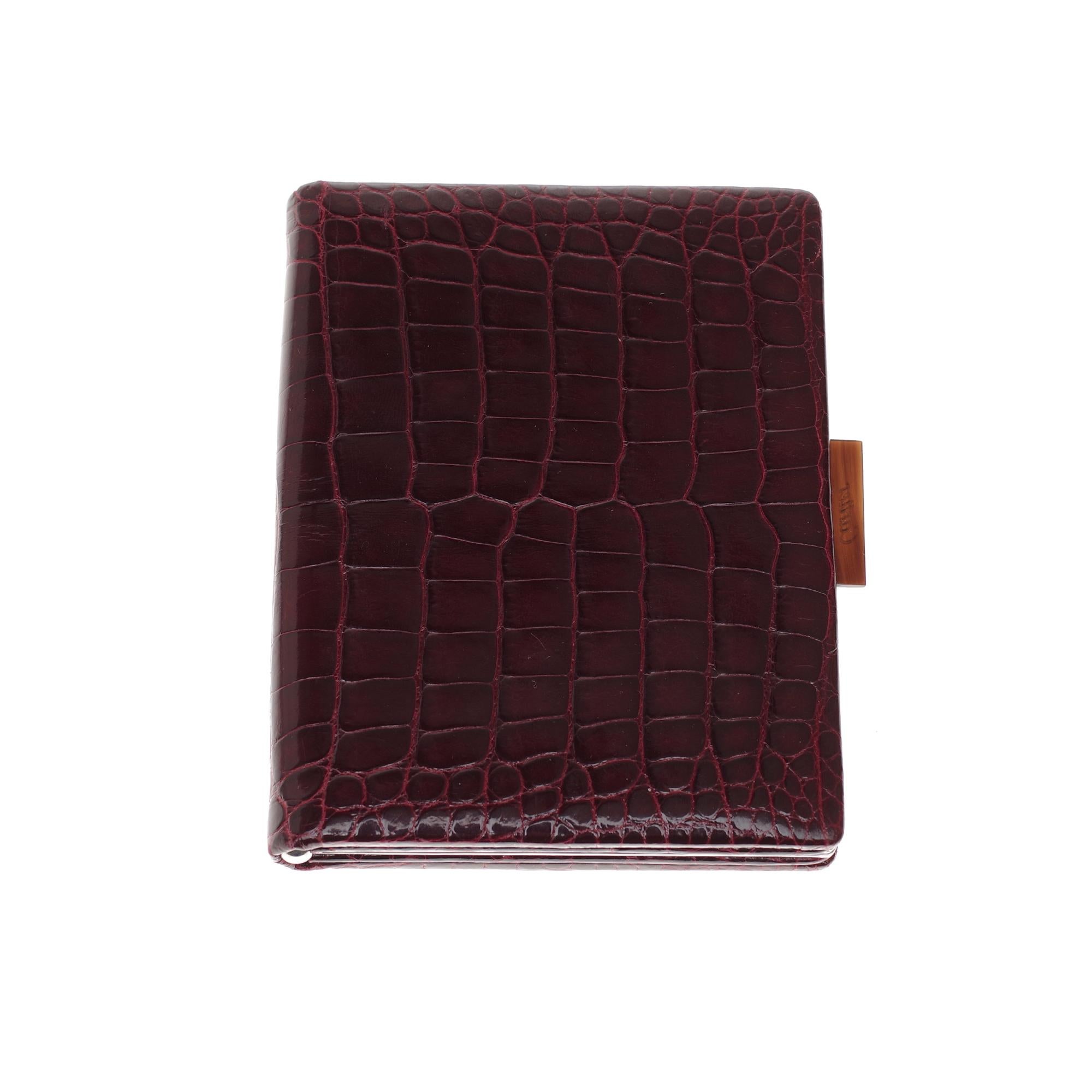 Cartier wallet in crocodile leather (crocodylus porosus, II/B) burgundy.
Burgundy leather interior, one coin compartment with snap closure, two card compartments, 1 patch pocket.
Silver-plated metal frame and black embossed push-button