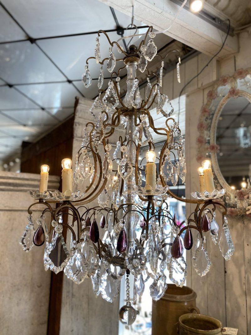 Wonderful old French chandelier, formed in brass. Dating back to circa 1900, and with elegant varying sizes of leaf-shaped and rosette and grape shaped faceted prisms.

Beautifully decorated with violet hued prisms and 8 lighting branches, causing