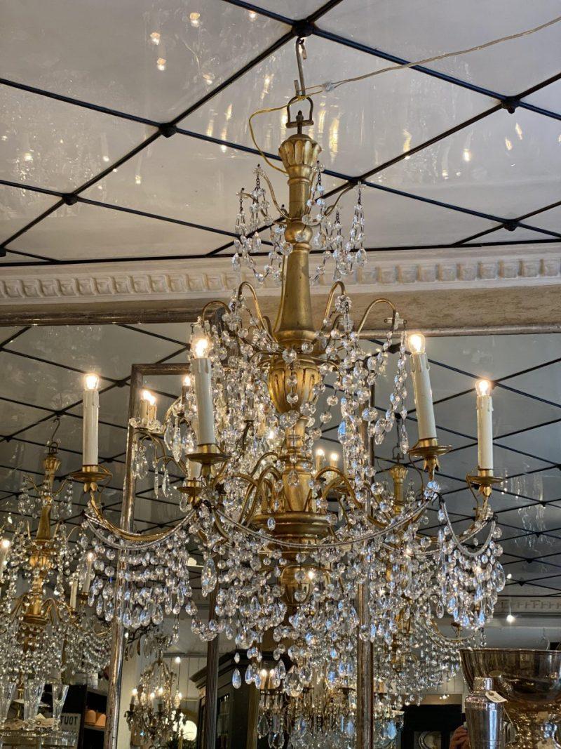 Antique French chandelier, dating back to circa 1900. A gorgeous gilded wood stem, and and gilded metal framework.

This lovely piece has a true opulence of beautifully faceted translucent prism chains, elegantly catching and casting light from the