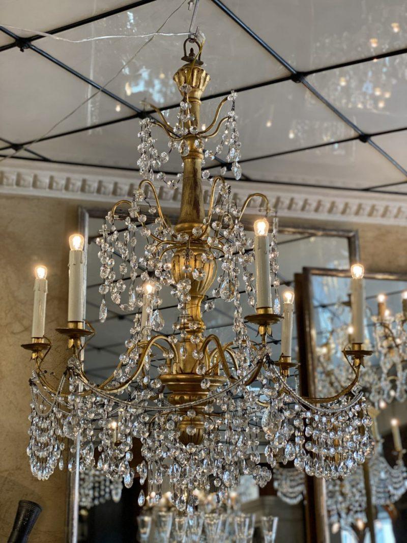 Antique French chandelier, dating back to circa 1900. A gorgeous gilded wood stem, and and gilded metal framework.

This lovely piece has a true opulence of beautifully faceted translucent prism chains, elegantly catching and casting light from the