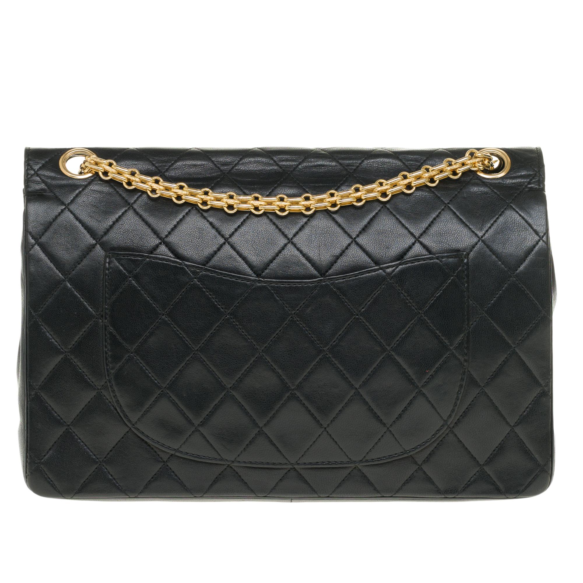 Beautiful Chanel Timeless Handbag 27cm with double flap in black quilted lambskin leather, gold metal trim, a Mademoiselle chain handle in gold metal allowing a hand or shoulder support.

Closure with gold metal flap.
A patch pocket on the back of