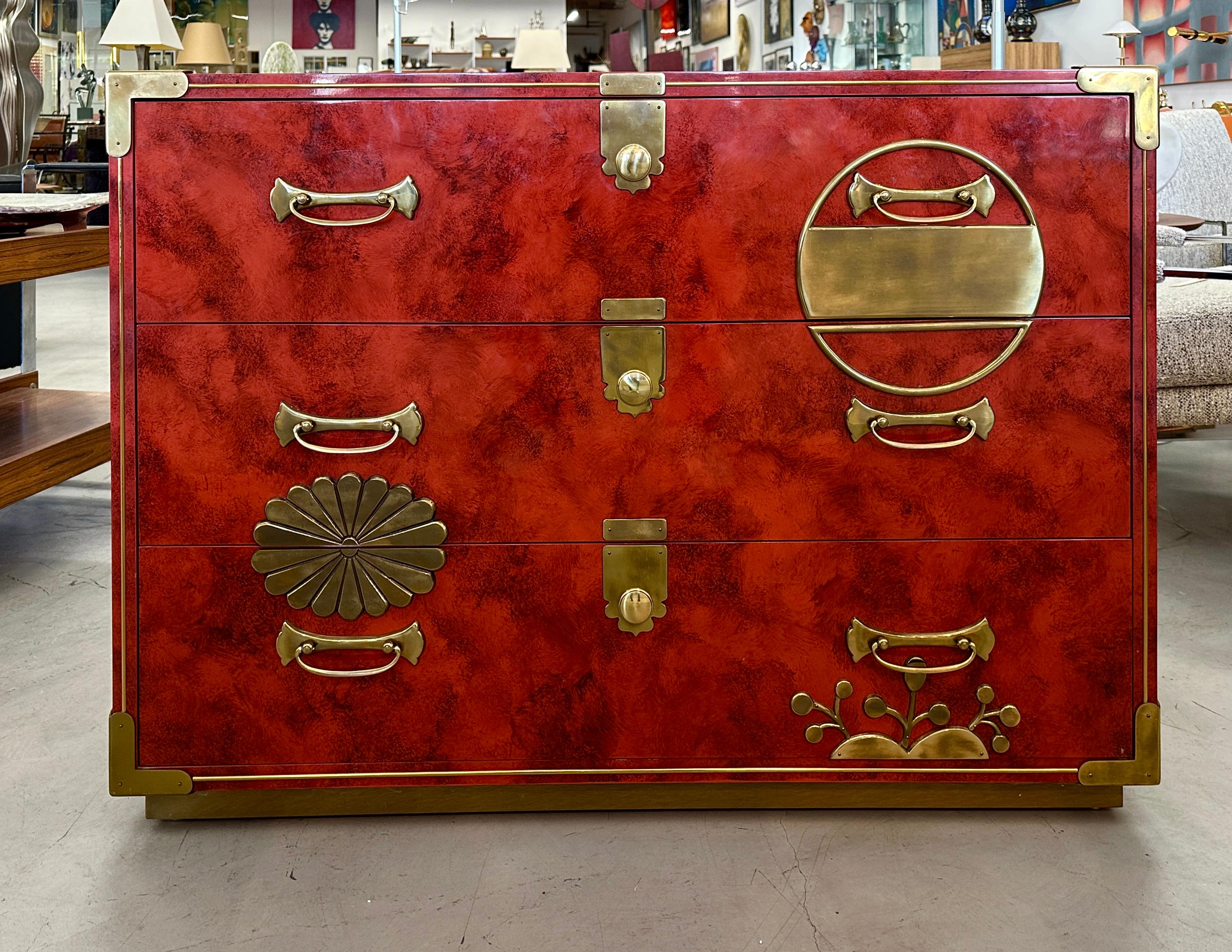 A stunning coral red lacquer chest by Mastercraft. It features beautiful brass fittings and  brass corner braces. It is sitting on a brass covered plinth base. Overall pretty Asian motif with oak secondary woods. Great overall Mastercraft quality,