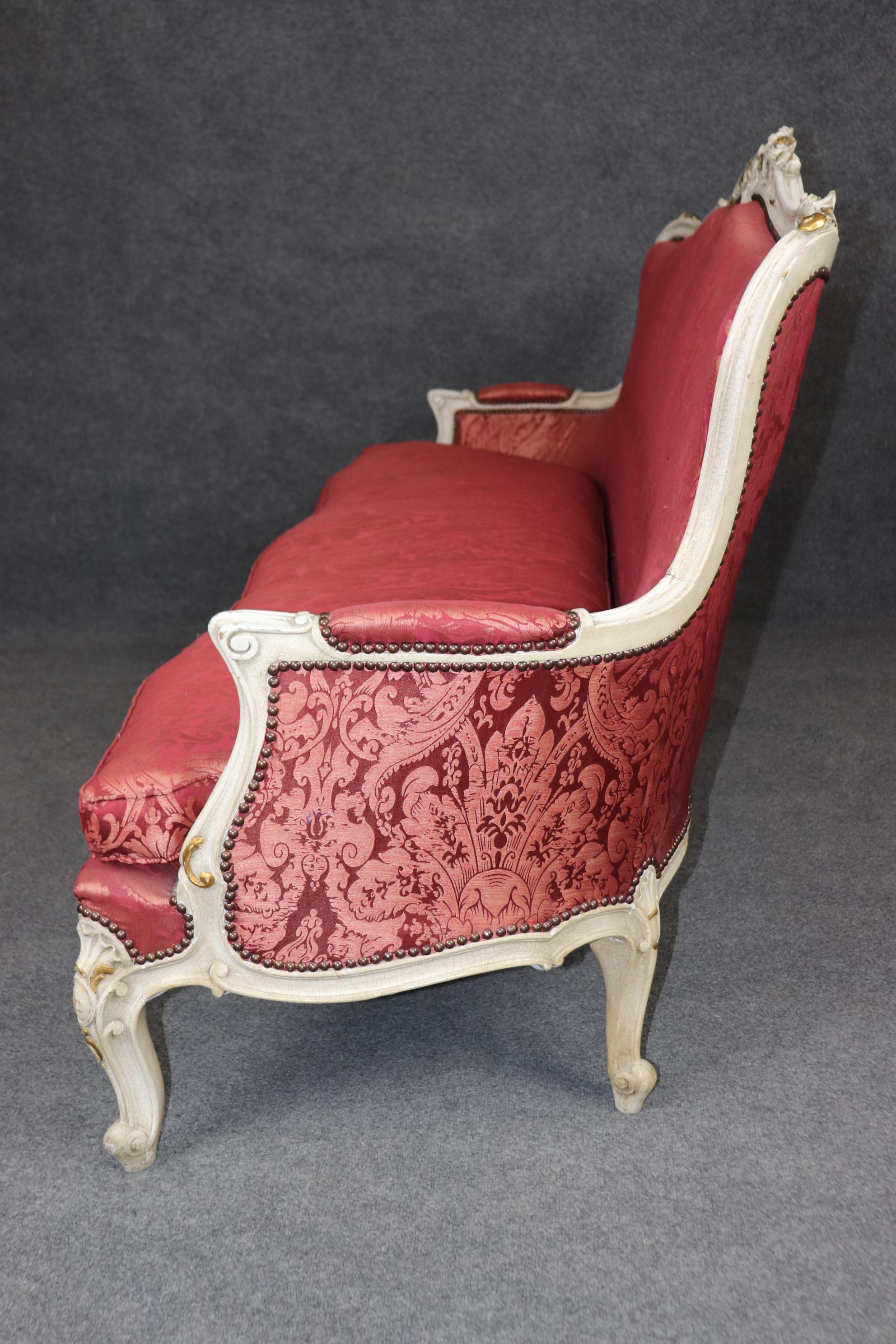 Il s'agit d'un superbe canapé avec une tapisserie en soie rouge et de subtiles touches de feuilles d'or. Les 4 chaises assorties sont vendues séparément. Le canapé est en bon état vintage avec des signes mineurs d'âge et d'usure et la tapisserie est