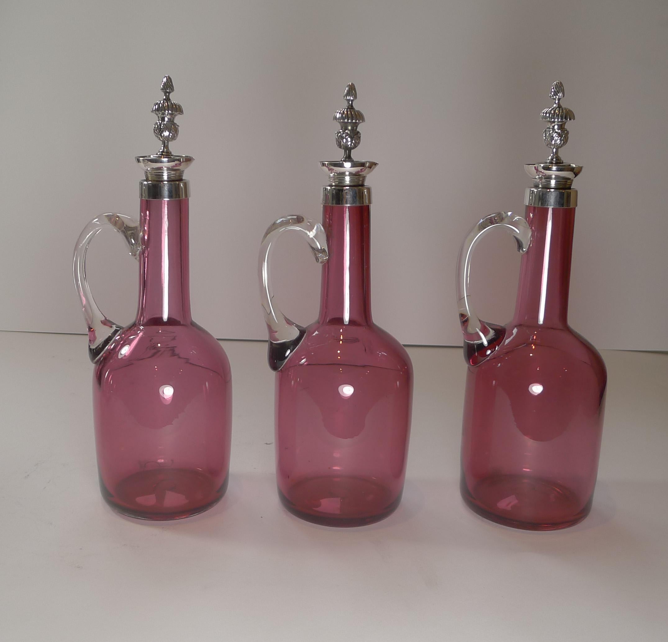 The silver plated caddy stands on exquisite feet and the three decanter holders beautifully pierced or reticulated.

The three cranberry glass decanters, each with a clear glass handle are topped with their original stoppers.

Dating to c.1890,