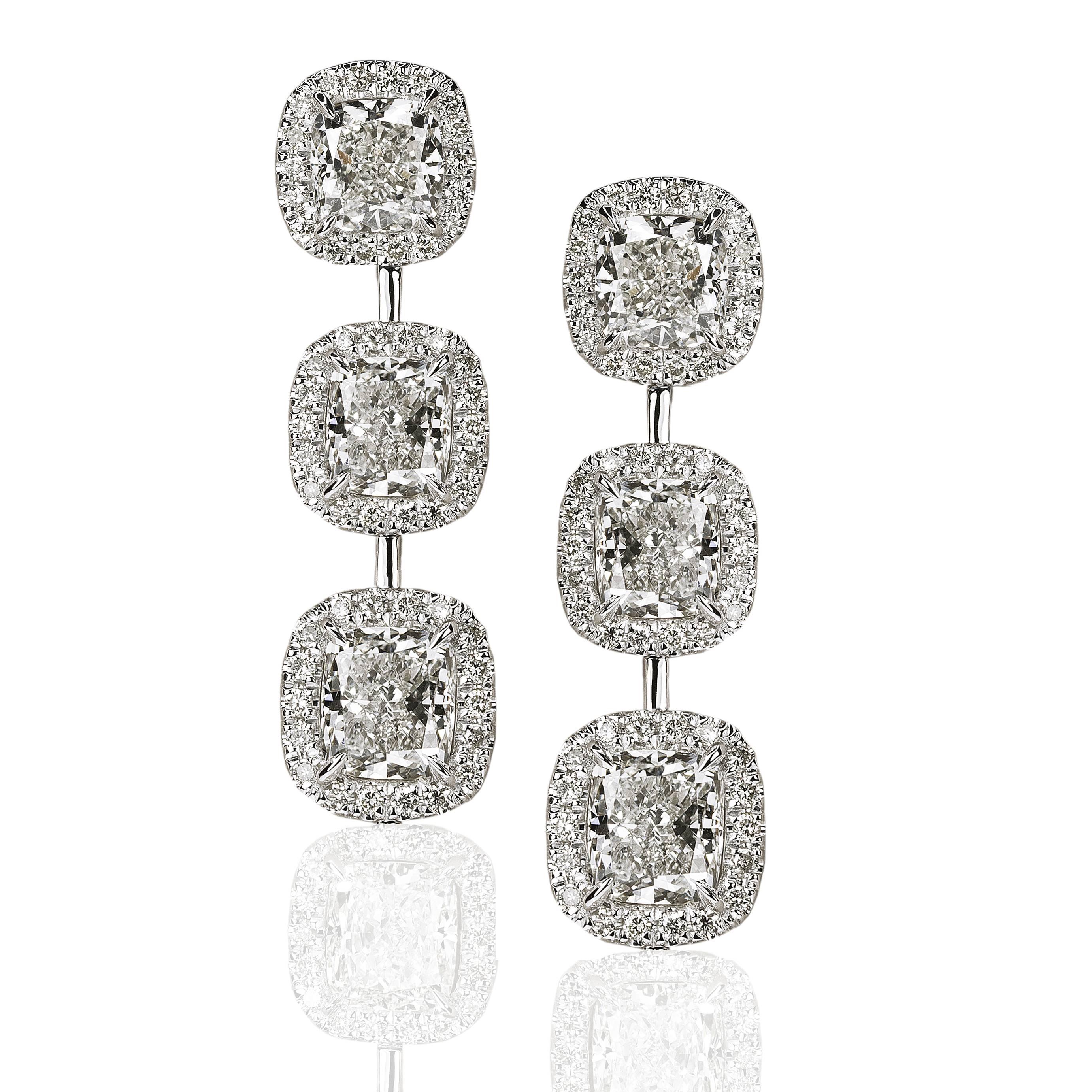 Stunning 18k earrings set with six cushion brilliant cut diamonds weighing 6.35 carats, each surrounded by  round brilliant diamonds totaling 0.78 carats.
