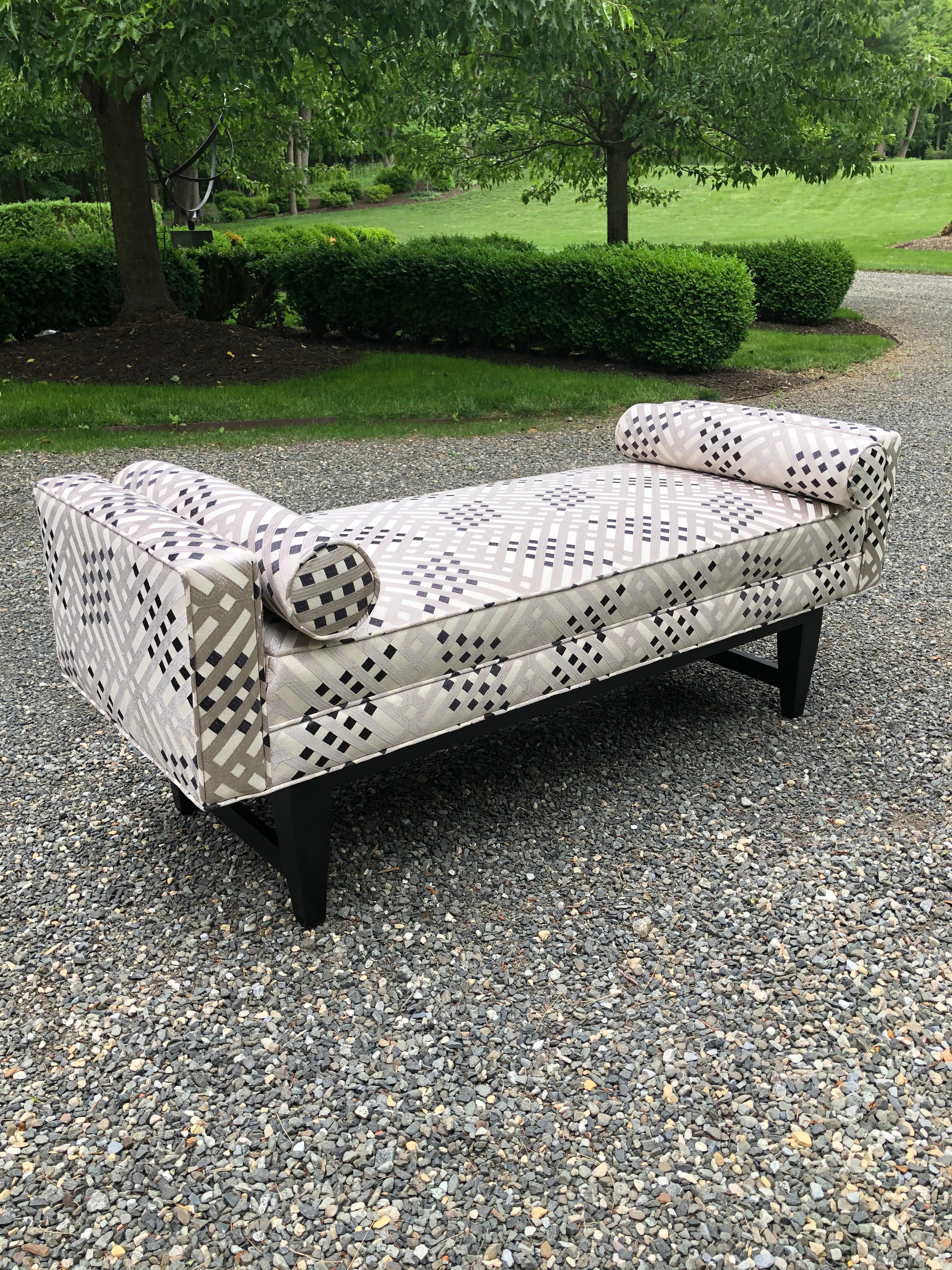 Custom settee bench in new colefax and fowler upholstery. Upholstery is a silvery grey, white and black lattice. Bench has straight arms and ebonized legs giving it a clean, elegant look. Rolled accent cushions.